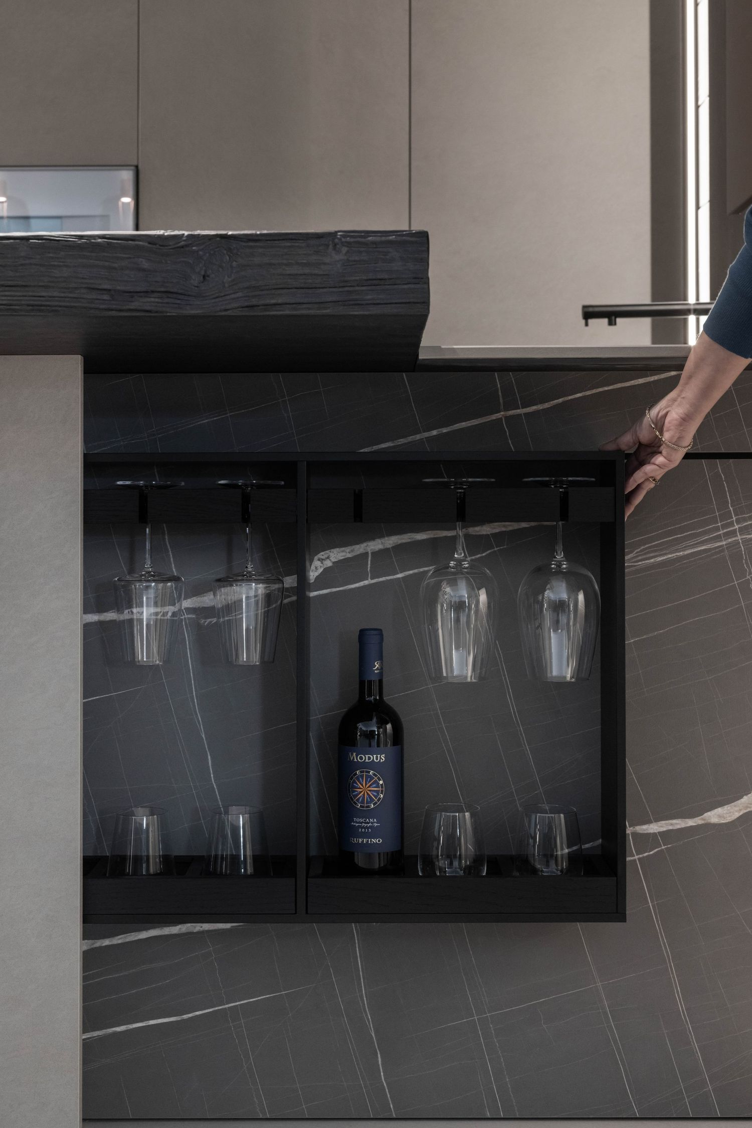 Hidden wine glass storage cabinet with black interior and bottle display.