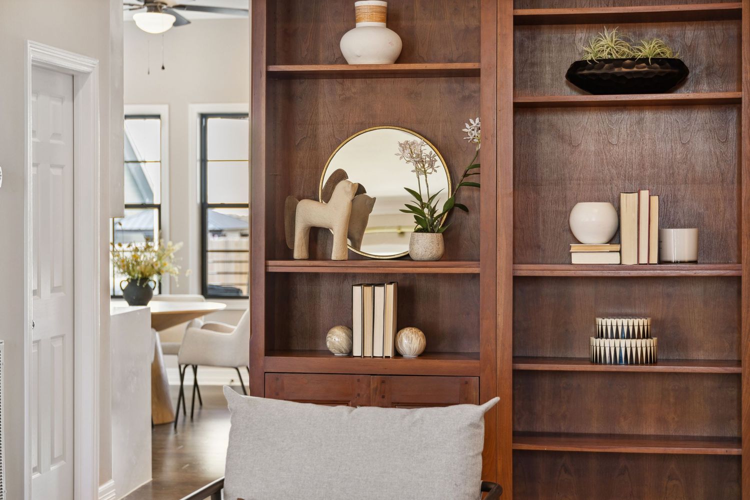 Warm wooden built-in shelving unit styled with minimalist decor and books.