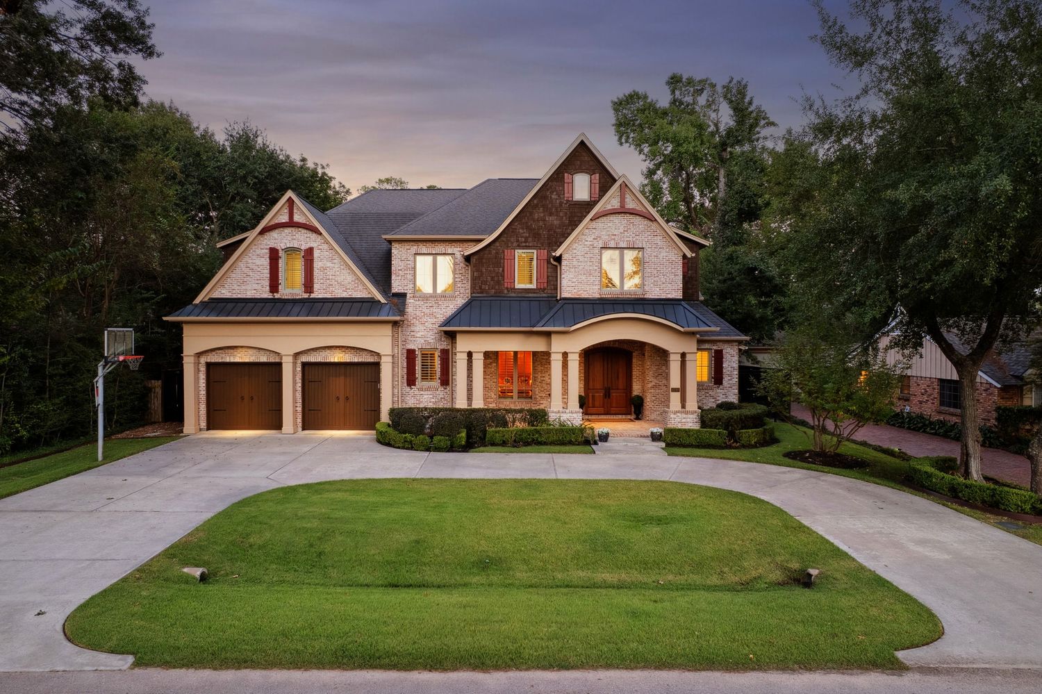 Dusk exterior shots of upscale residential homes with large driveways and architectural features.