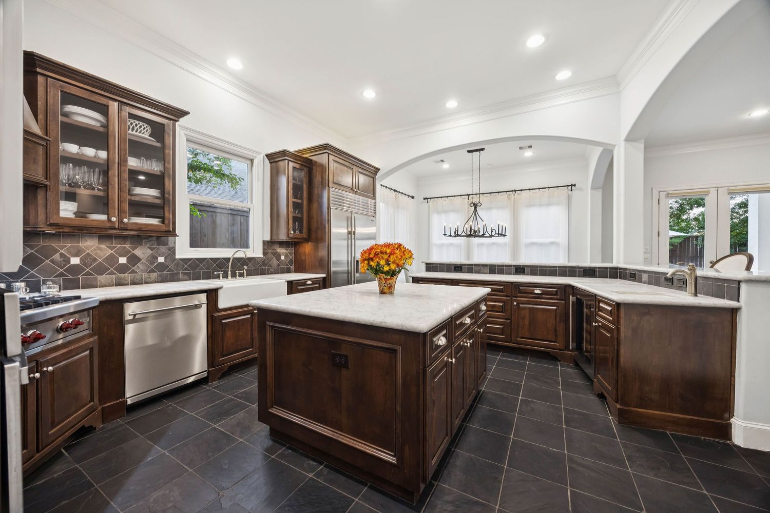 Luxury kitchen with dark wood cabinets, stainless steel appliances, and modern lighting fixtures.