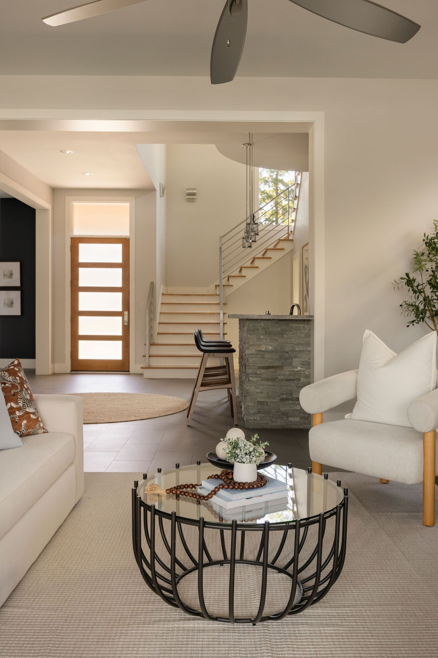 Open concept living space with carpeted floors, modern furniture, and wooden staircase.