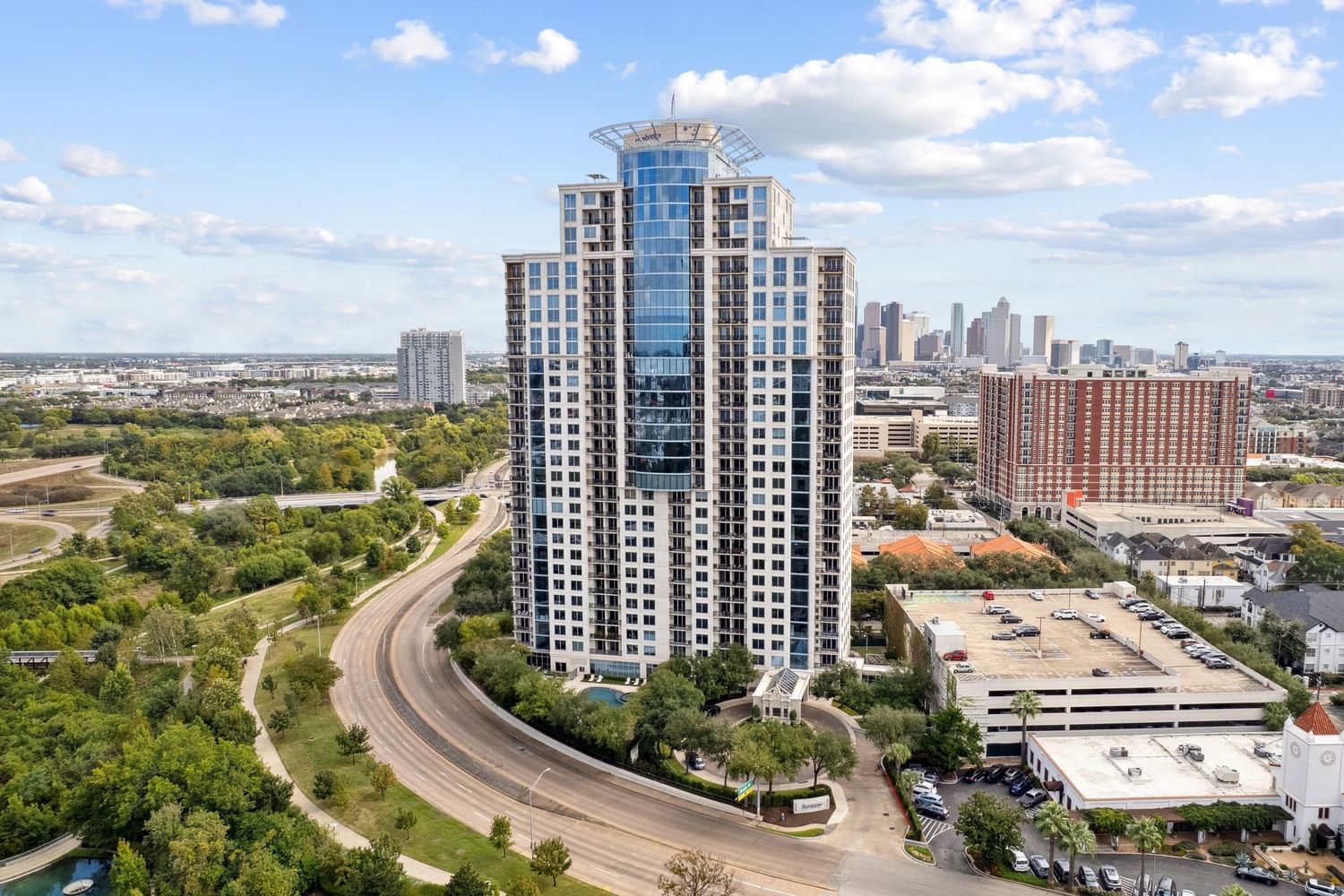 Modern high-rise residential tower with glass facade overlooking urban landscape.