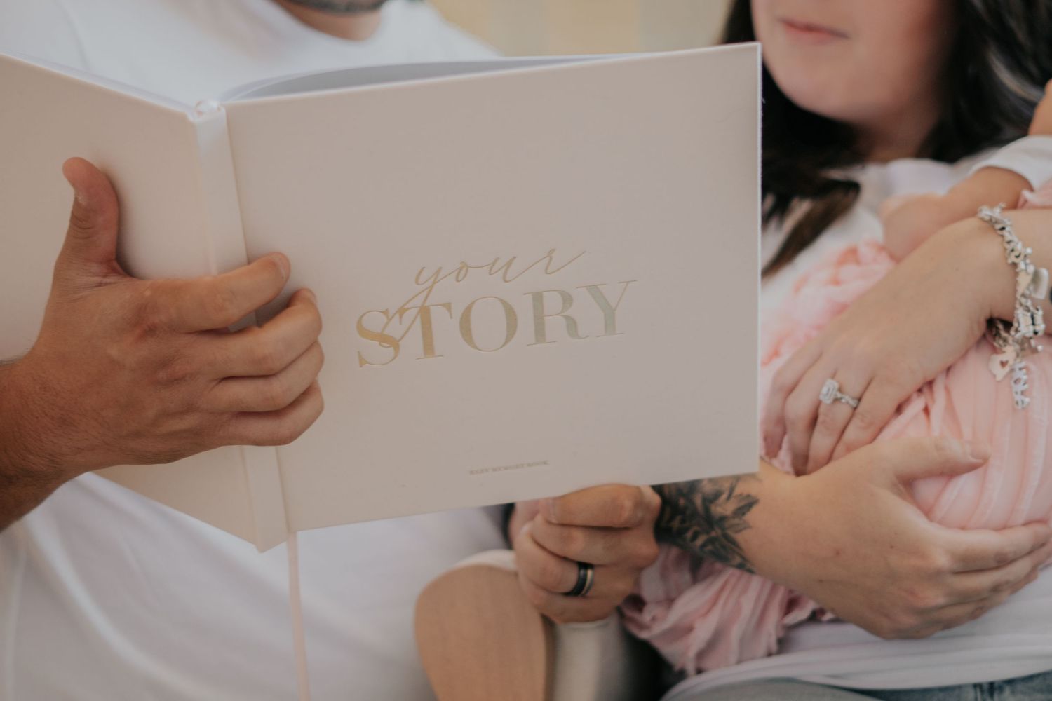 New parents holding a Your Story baby memory book during a newborn photo session.