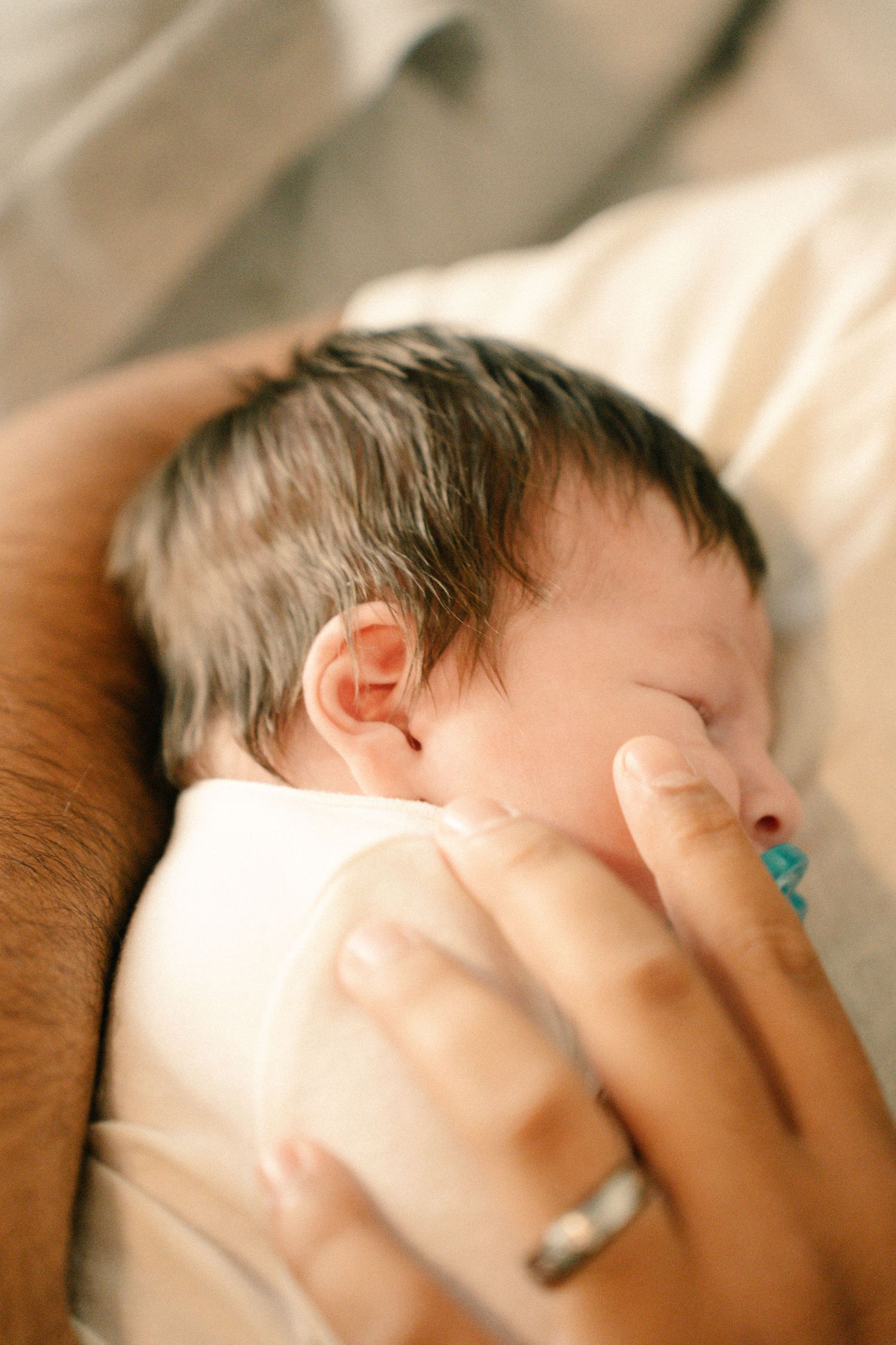 Newborn baby peacefully sleeping while being cradled and bottle-fed by a parent.