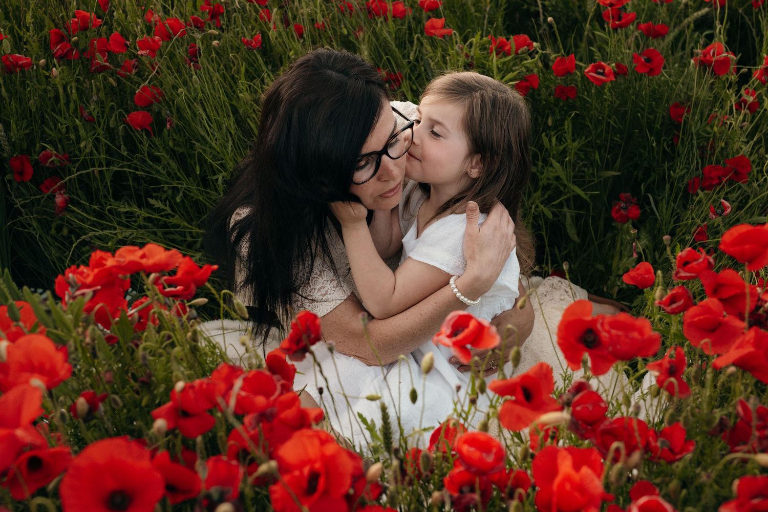 Moment de complicité entre une mère et sa fille dans un champs de coquelicots lors d'une séance photo à Béziers.