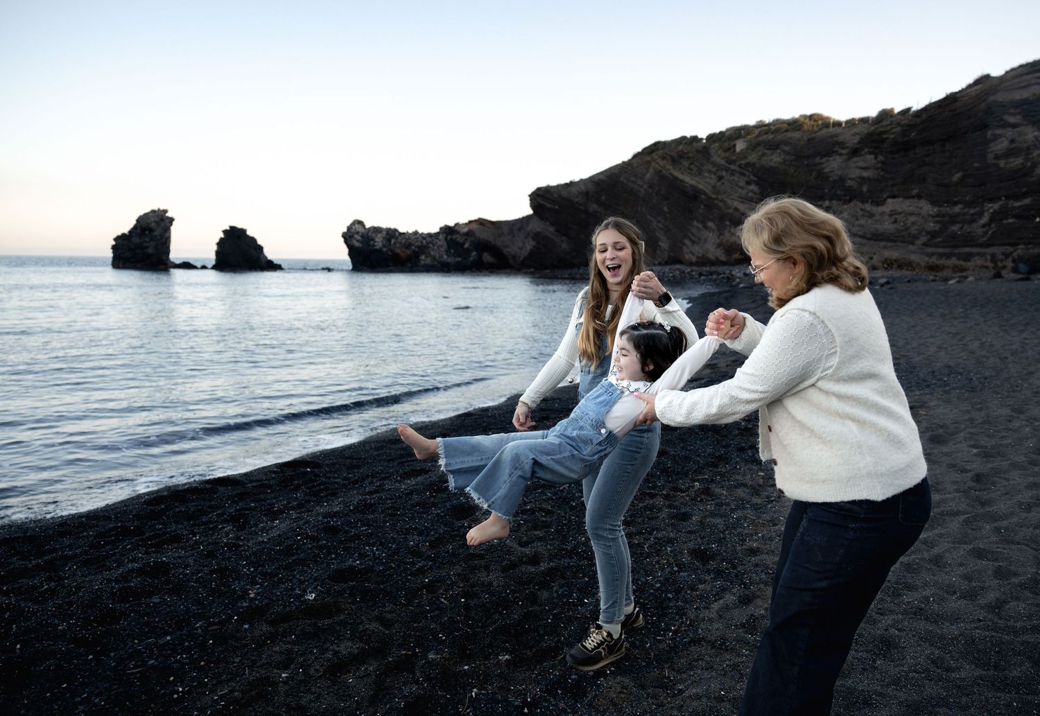 Maman et Mamie jouent avec bébé fille en bord de mer à Agde lors d'une séance photo lifestyle famille complice dans l'Hérault.