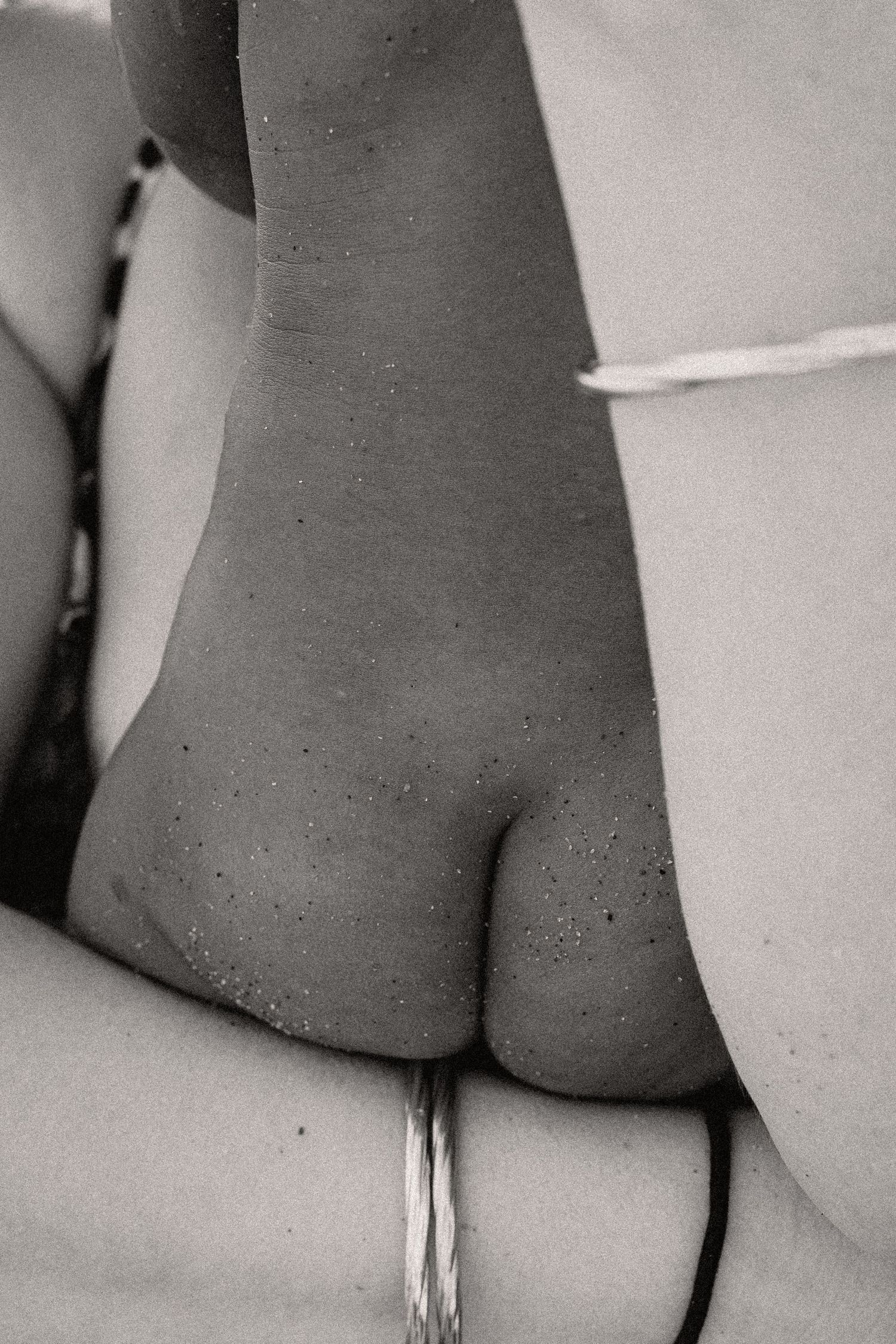 Photo en gros plan en noir et blanc d'un genou de sable avec des gouttelettes d'eau à la plage de Portiragnes proche de Agde et Béziers.