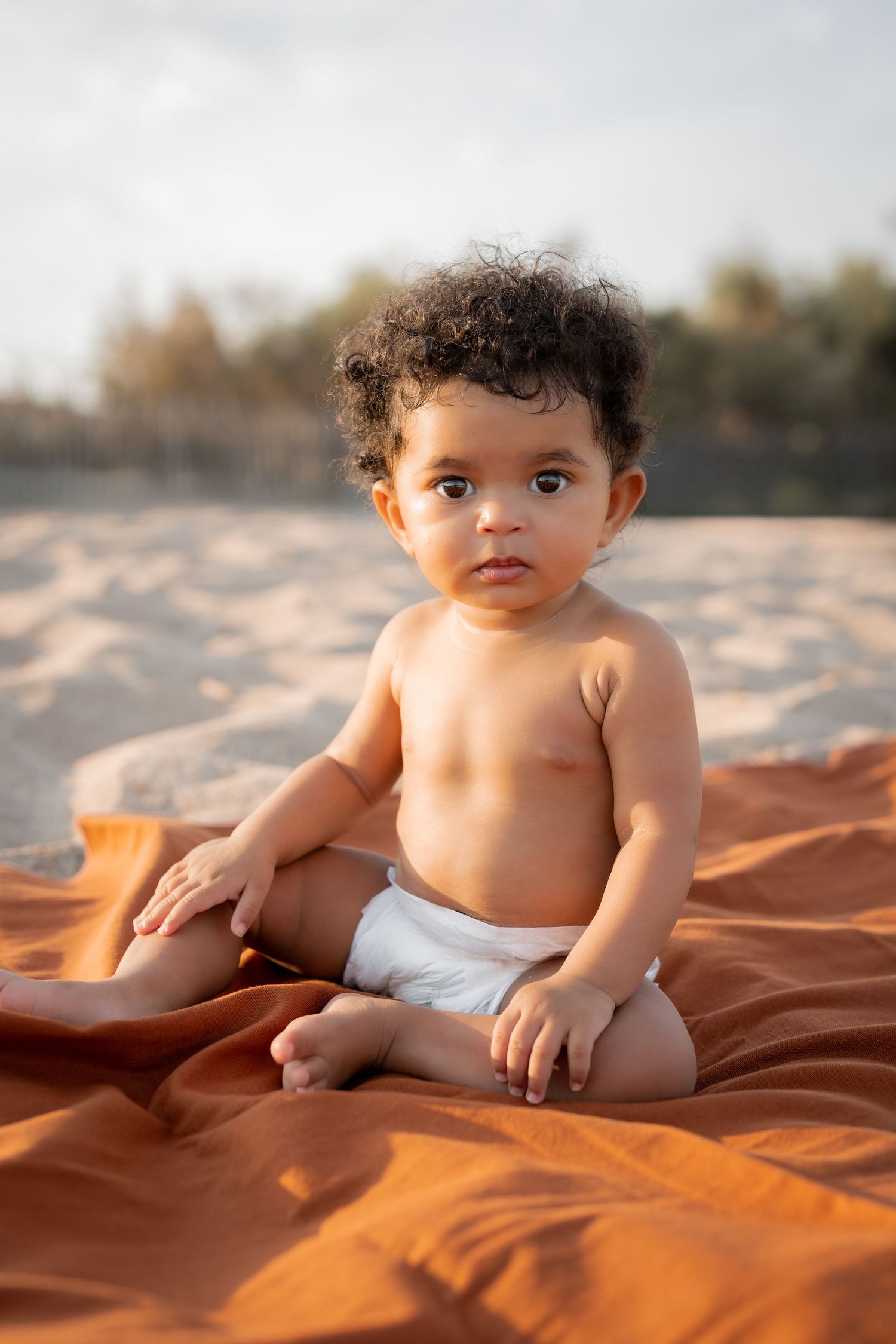 Adorable bébé métisse cheveux bouclés en bord de mer. Séance photo famille à Portiragnes. Portrait de bébé en bord de mer. Lifestyle.
