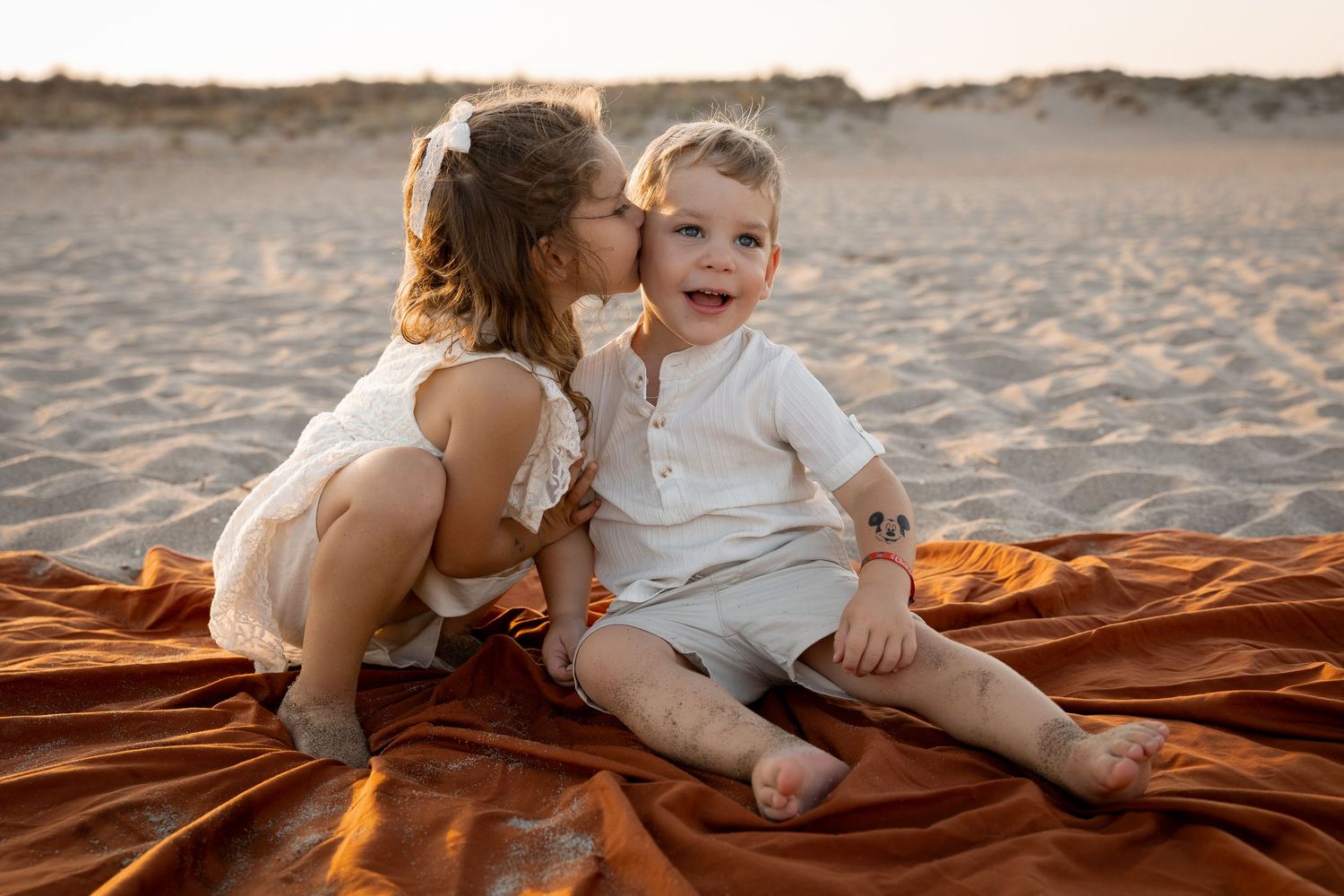 Photo d'un frère et sa soeur complices. Bisous d'enfants. Photographie de jeux d'enfants à Vendres, bord de plage, Hérault.