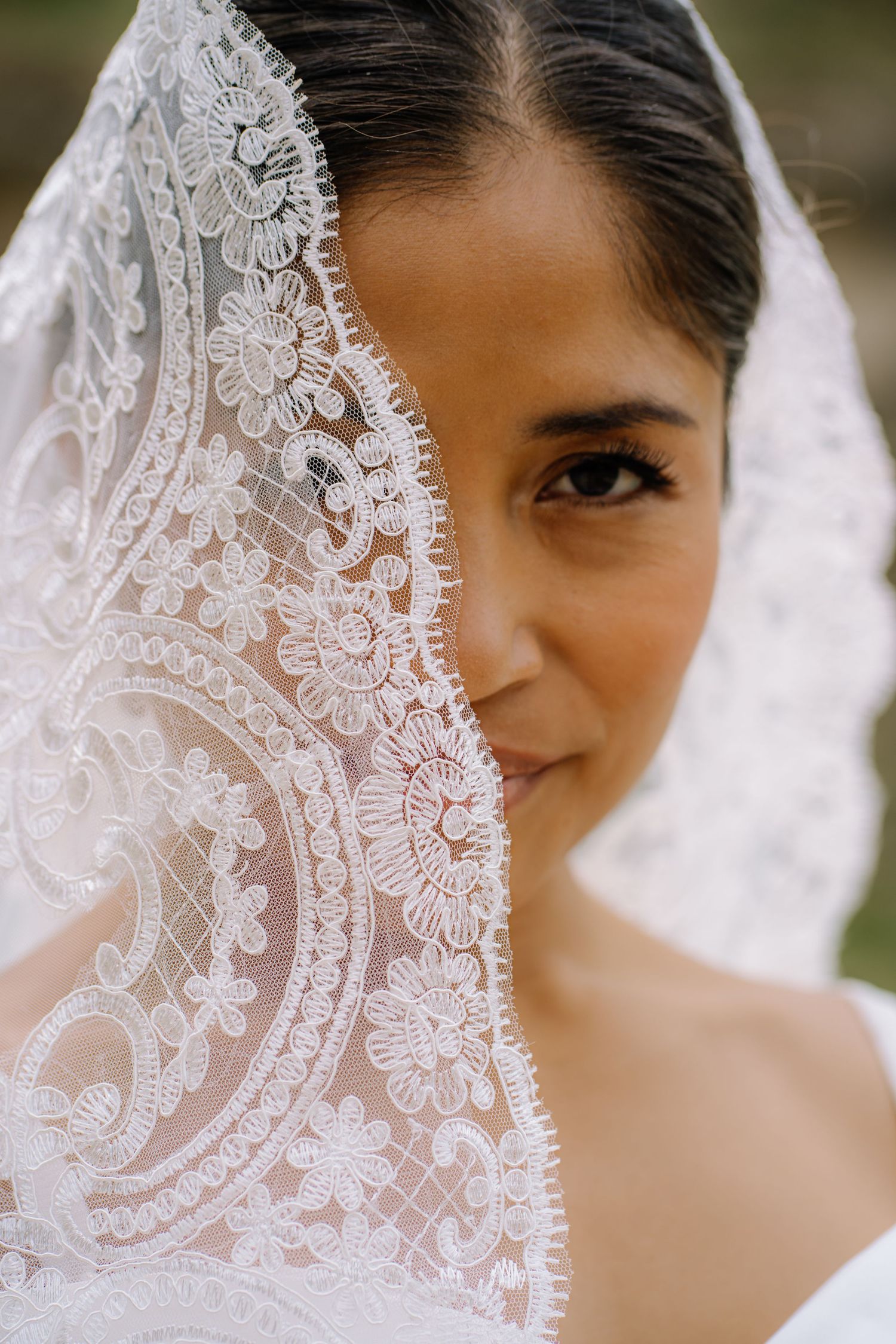 Close-up detail of intricate white lace veil with delicate floral patterns.