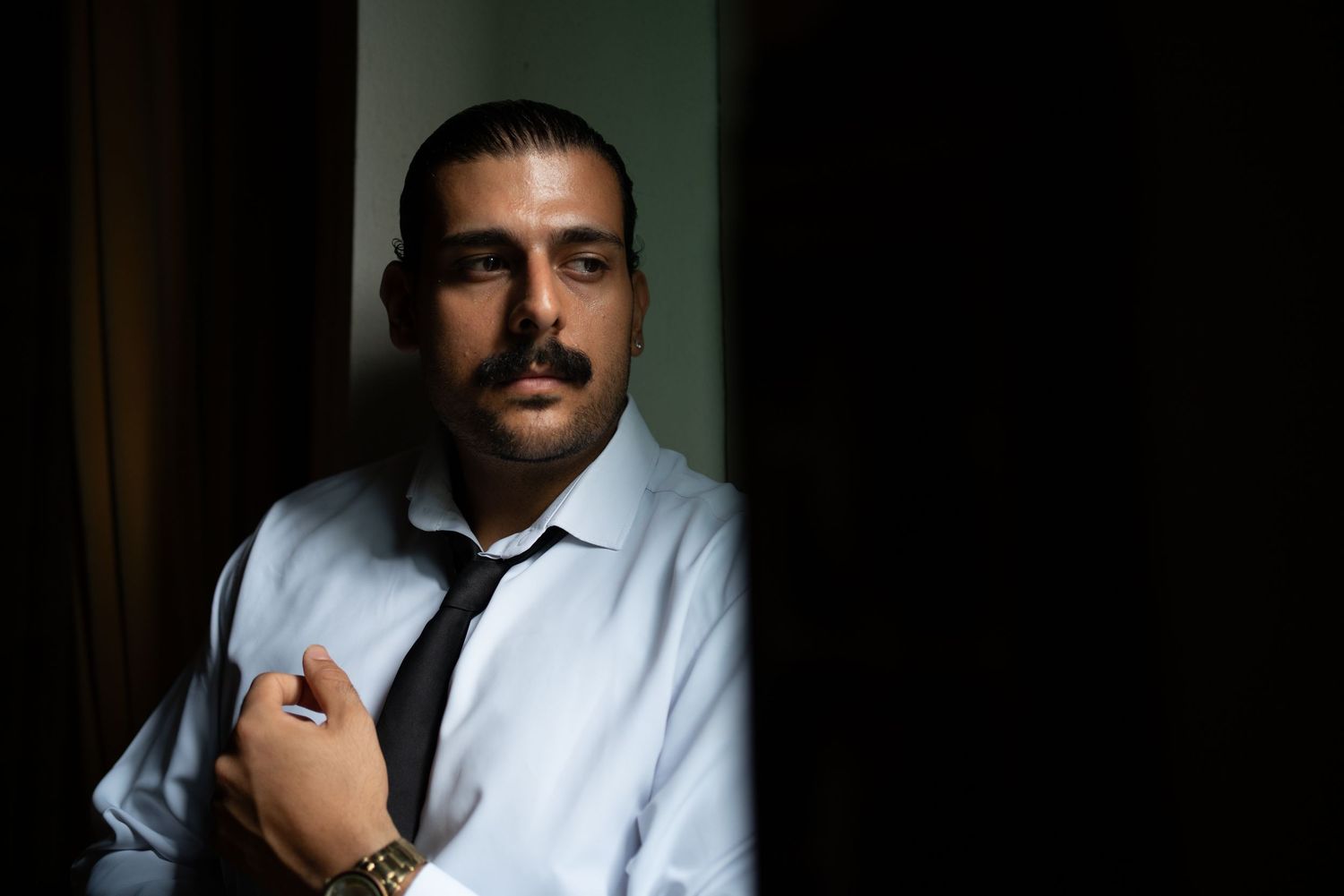 Professional portrait in white shirt and tie against dark background.