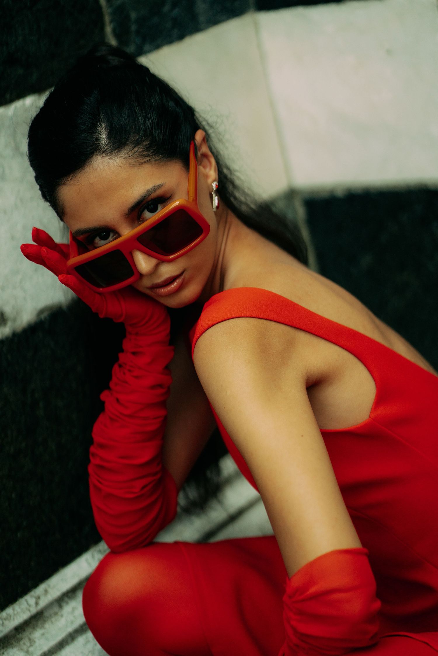 Artistic fashion photography featuring red dress and matching long gloves in moody lighting.