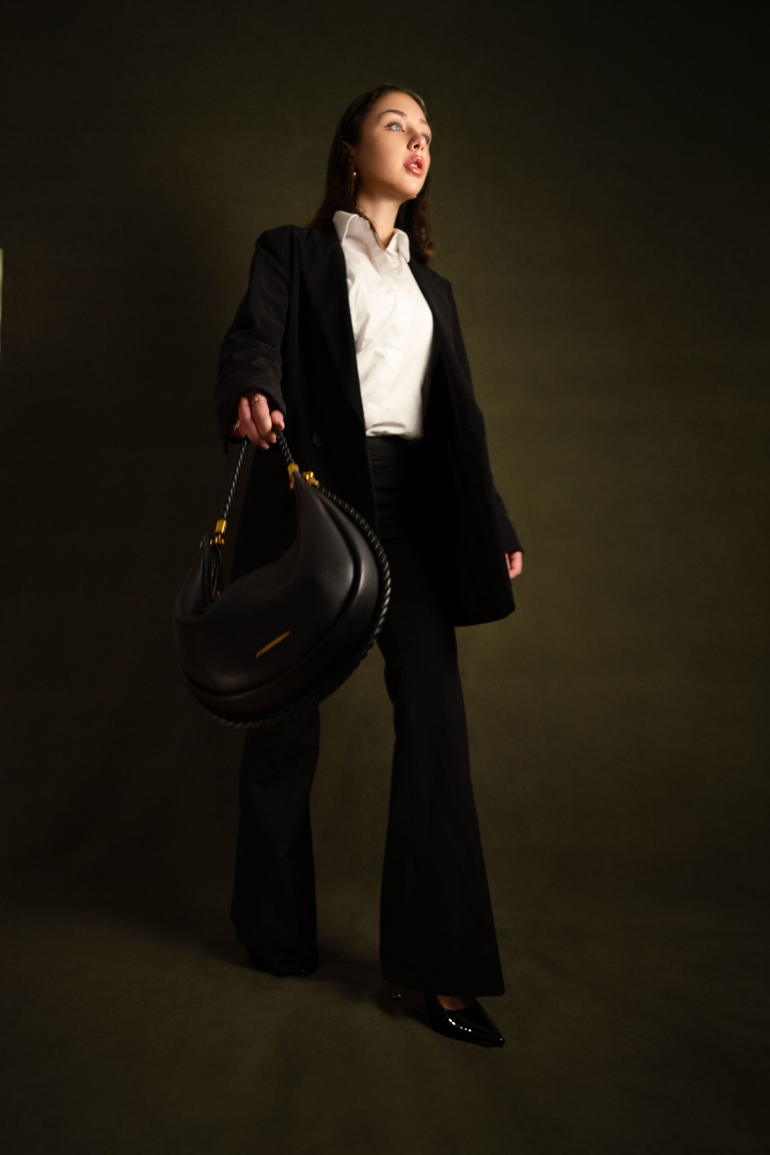 A dramatic fashion portrait in dark lighting shows a figure in a black suit and white shirt striking dynamic poses. Located in South France