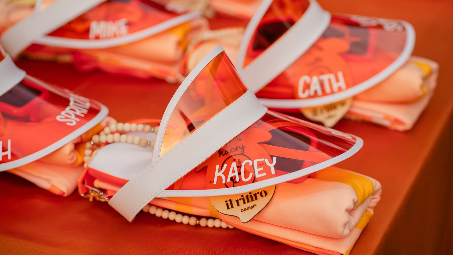 Orange gift bags with personalized name tags arranged on a table.