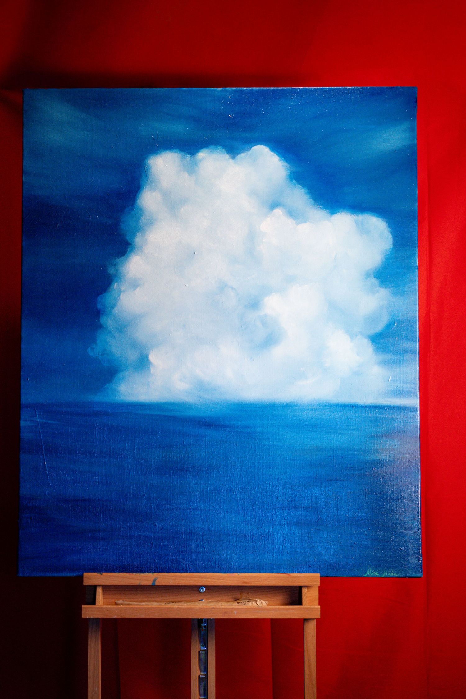 Progress shots of cloud painting on canvas against red wall.