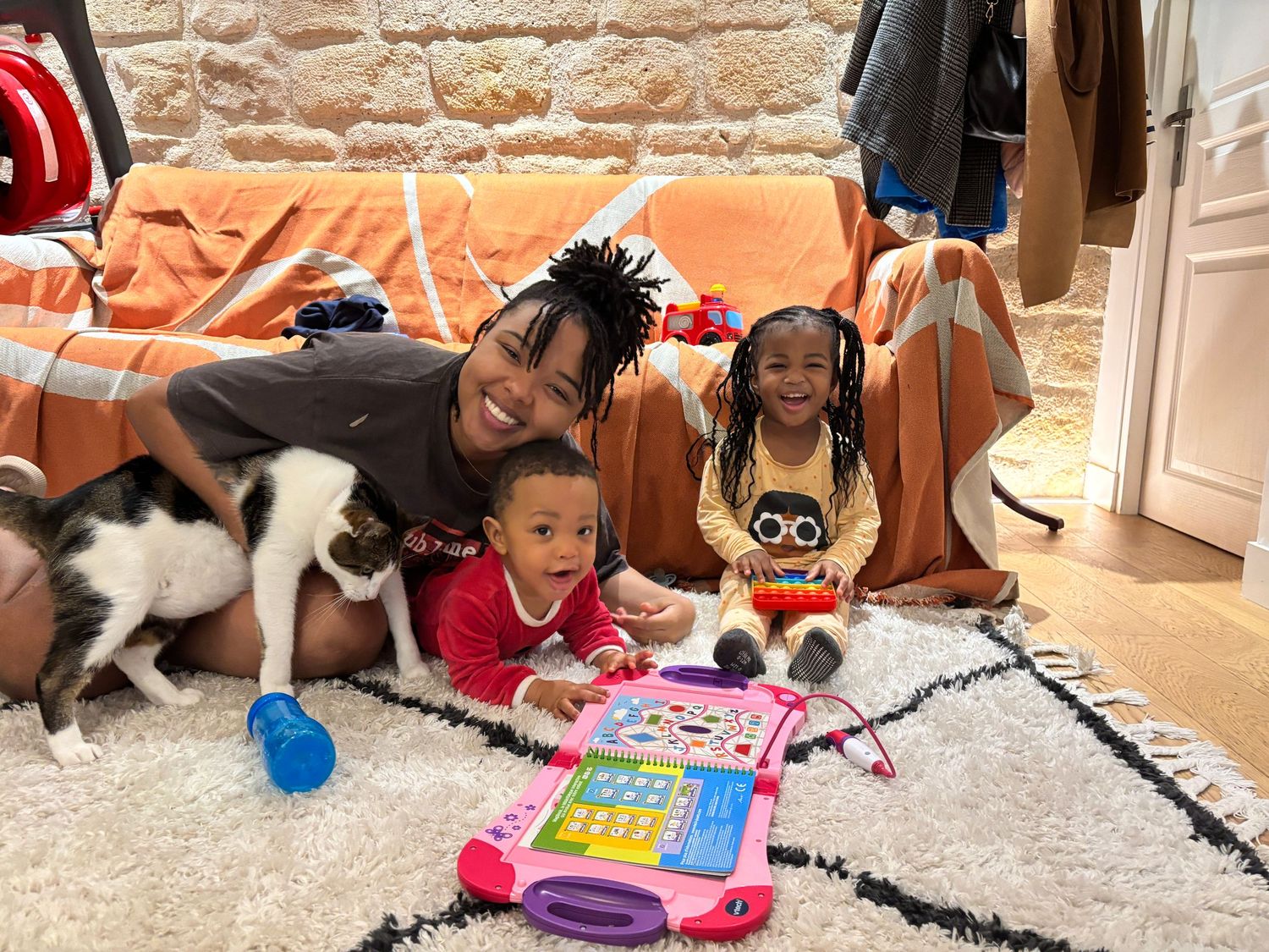 Family playtime on a patterned rug with toys and pets in Paris
