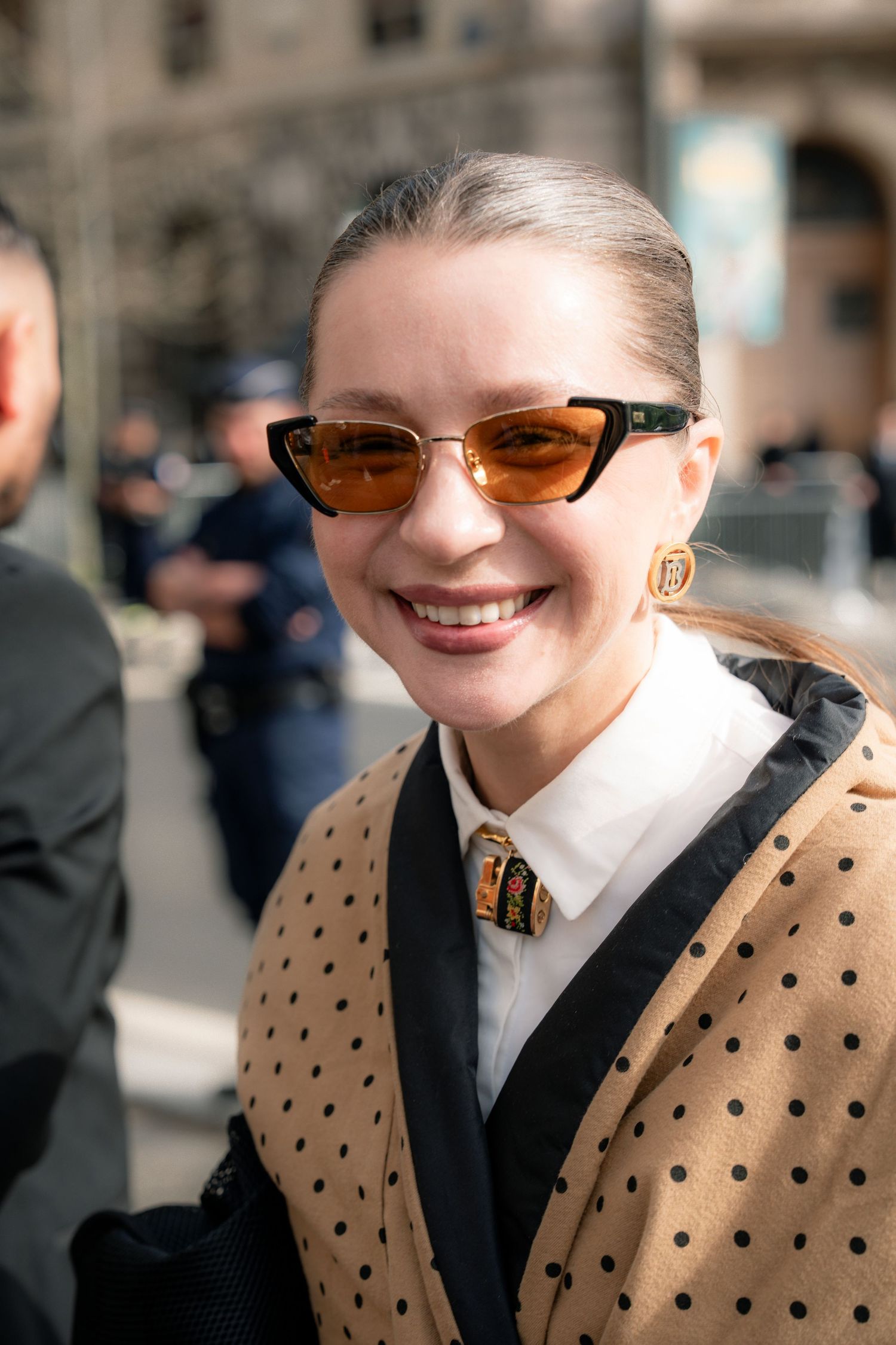 A series of photos showing someone wearing a polka dot cardigan, black tie and white shirt with tinted glasses.