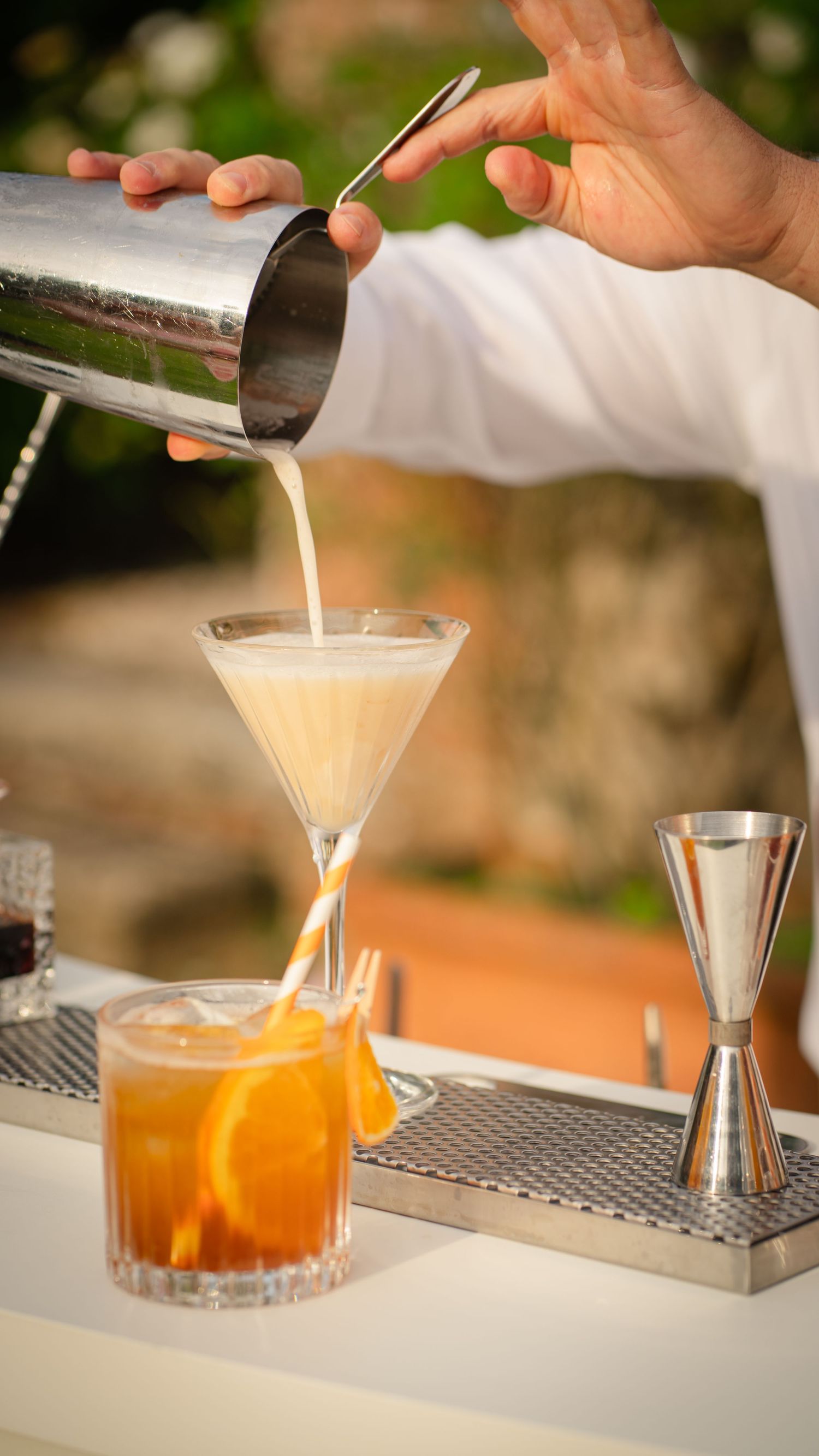Bartender pouring a layered cocktail into a martini glass with precision.
