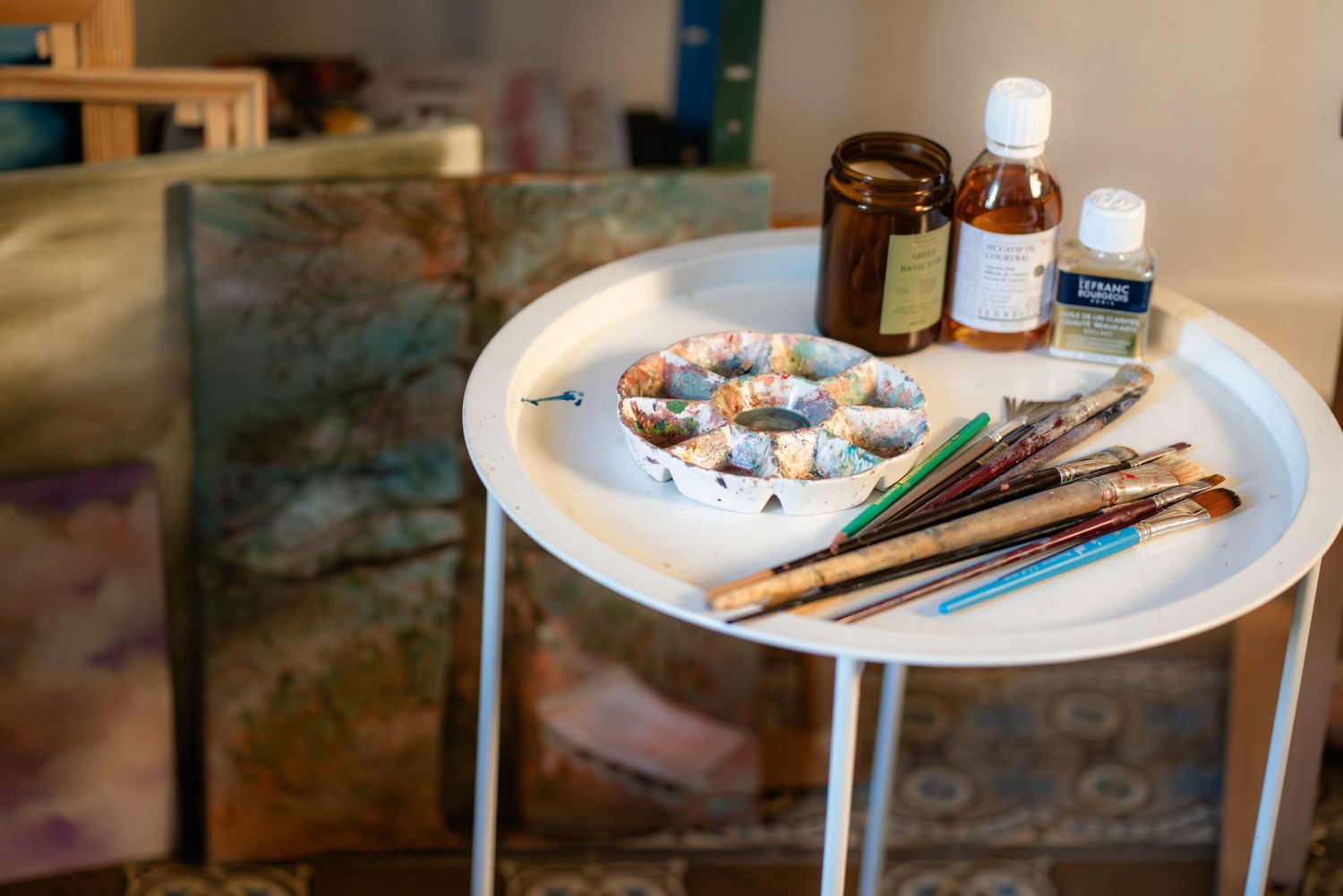 Art supplies and painting materials arranged on white round table.