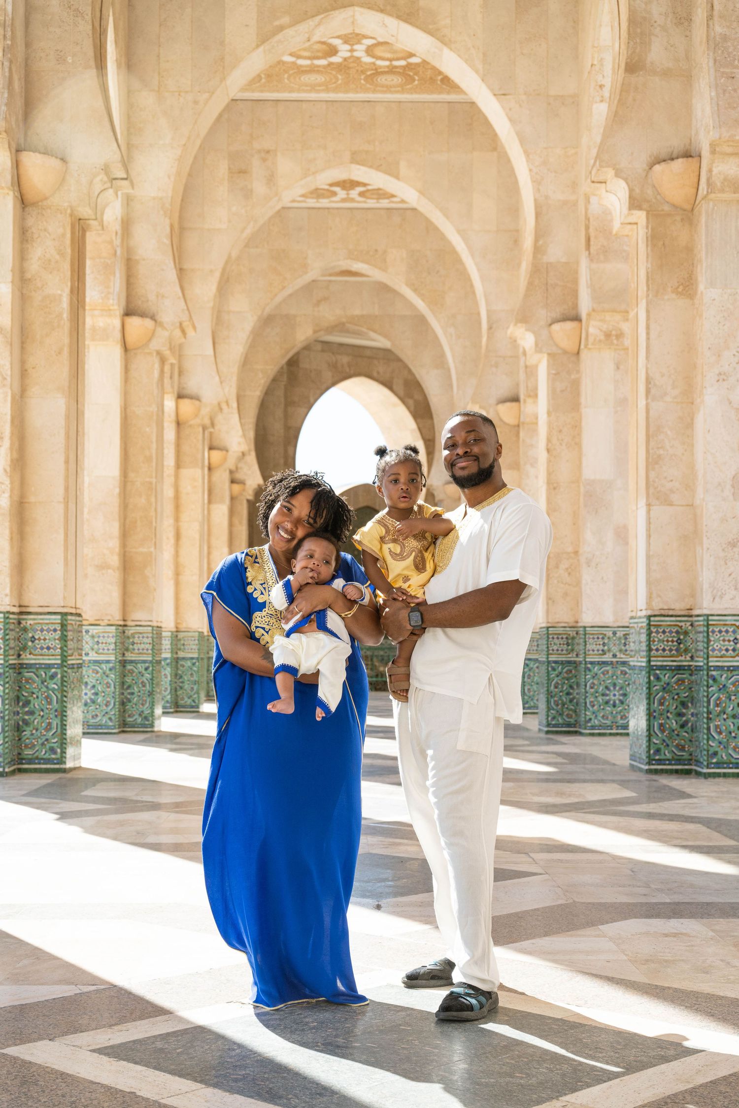 Family portrait under ornate Moroccan archways with decorative tile work.
