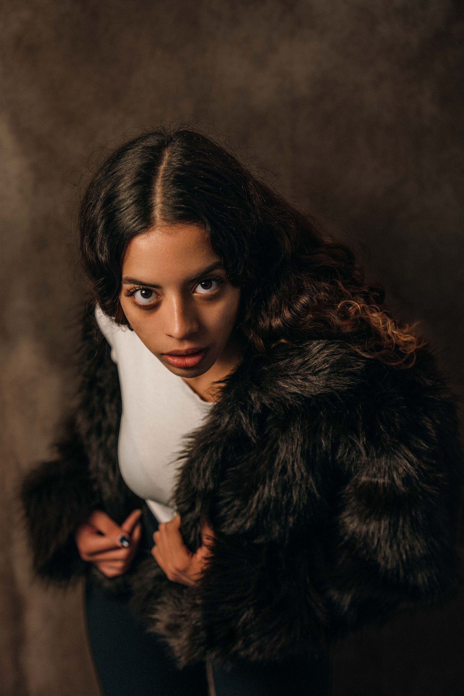 Artistic portrait series showing dark hair and black fur collar against moody brown background in multiple poses.
