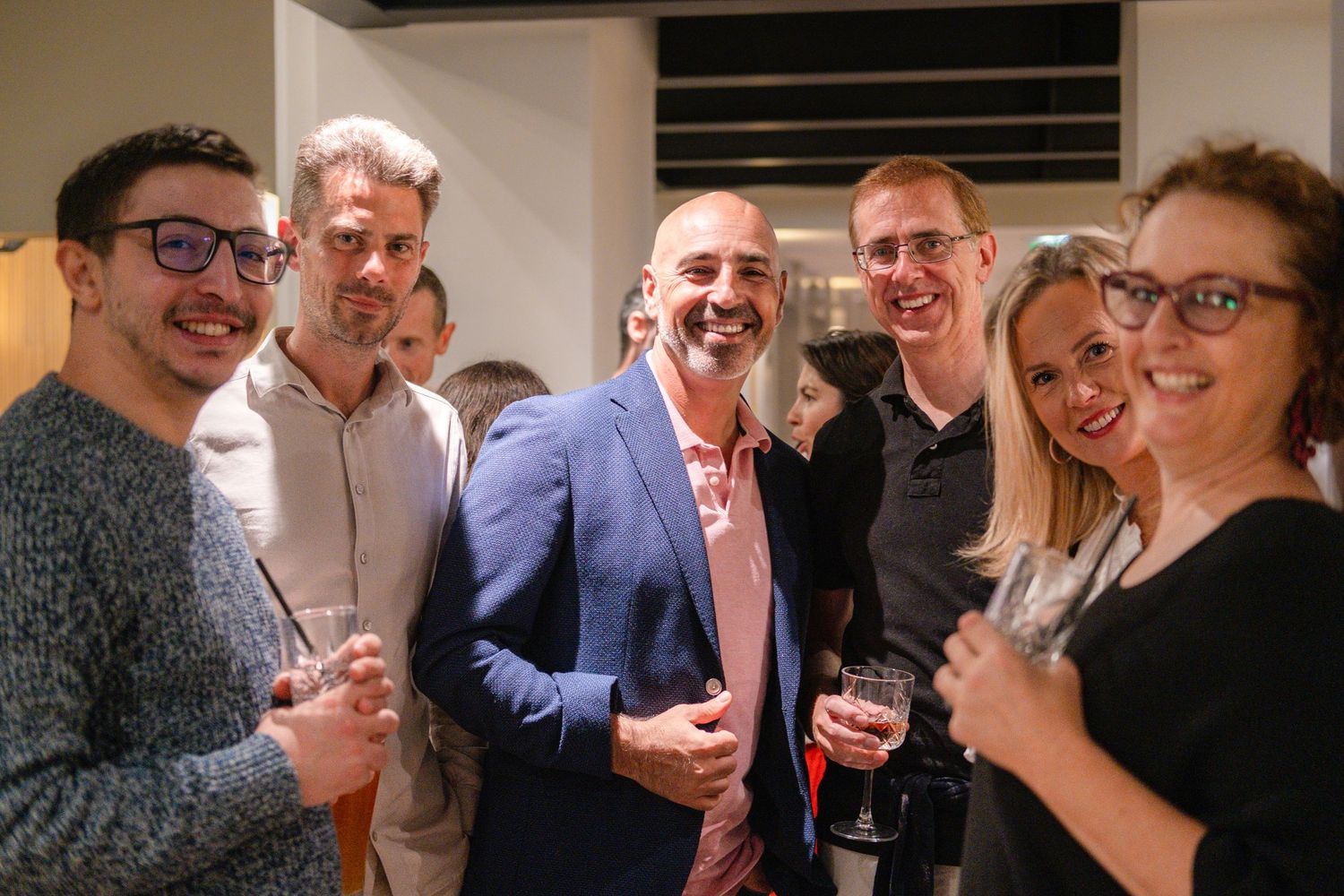 A group of people laughing and socializing at an indoor gathering or party.