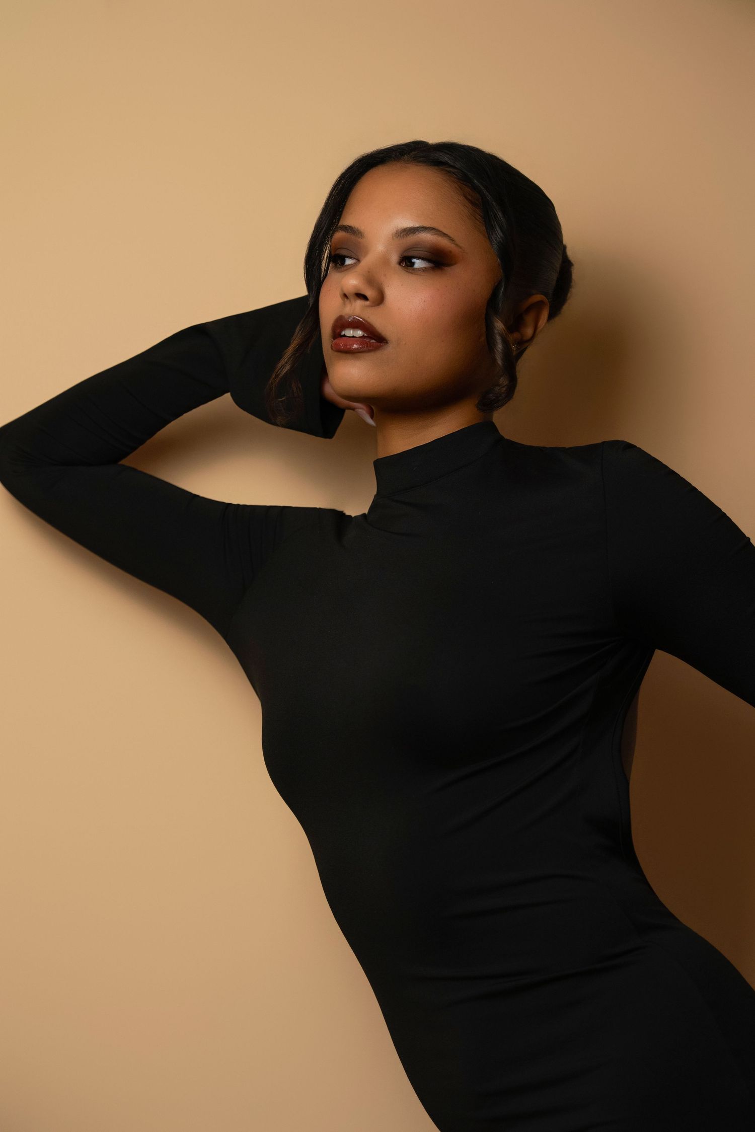 A series of artistic fashion portraits showing a model in a black long-sleeved dress against a beige background.