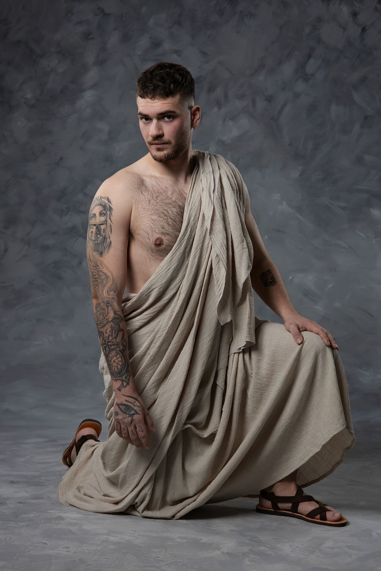 Artistic portrait series showing a model in a draped beige toga against a textured grey backdrop.