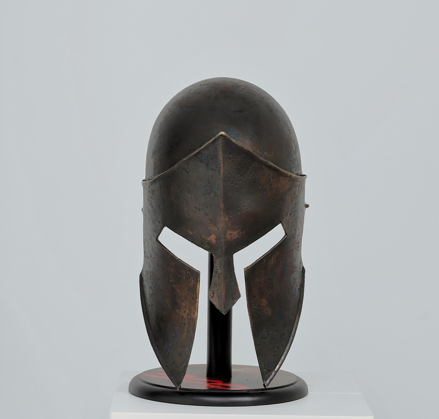 Themistocles-style ancient Greek warrior helmet with dark patina shown from front, side, and top angles, historical armor photography