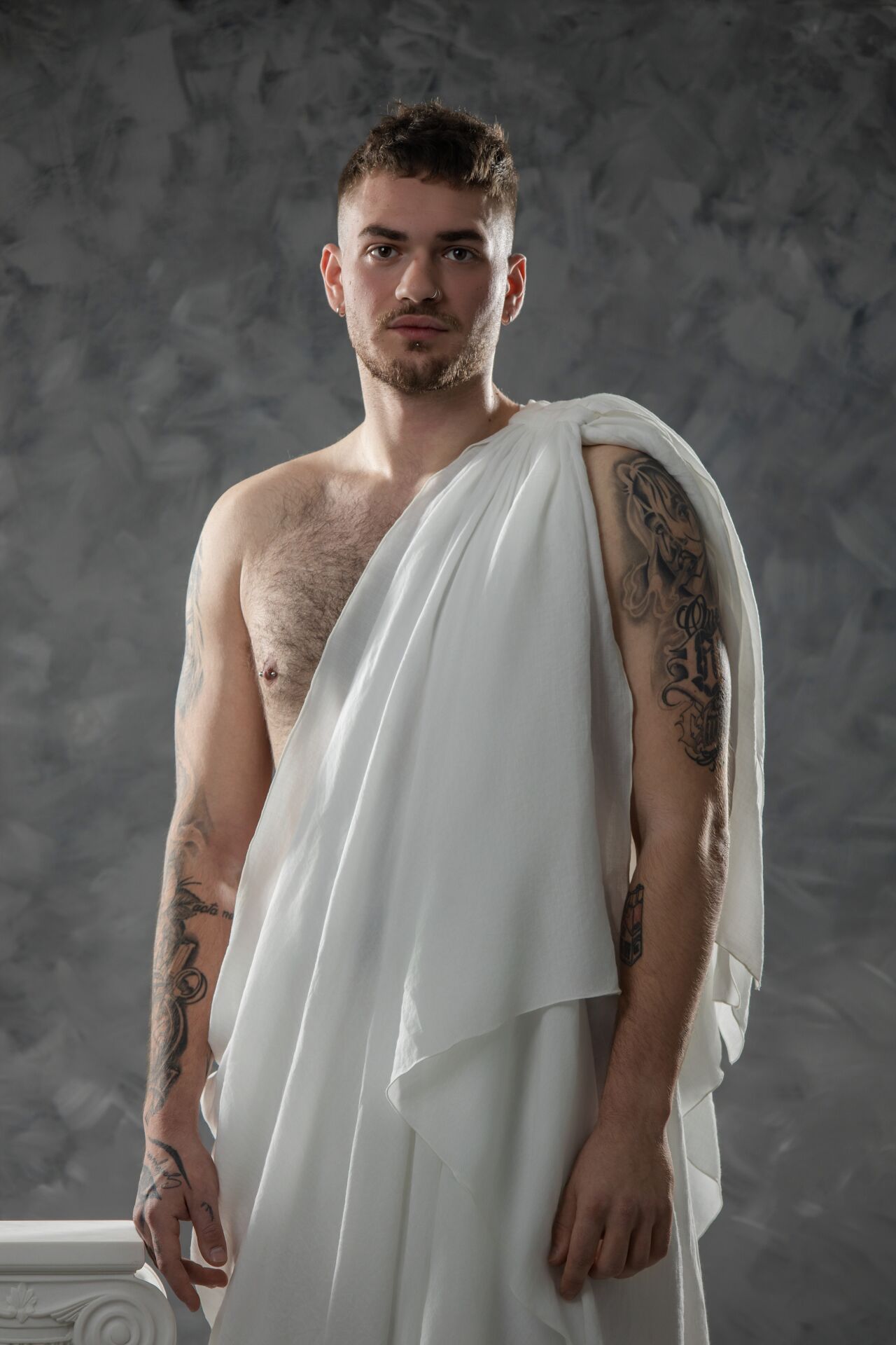 Artistic portrait series showing a shirtless person draped in flowing white fabric against a textured gray backdrop.