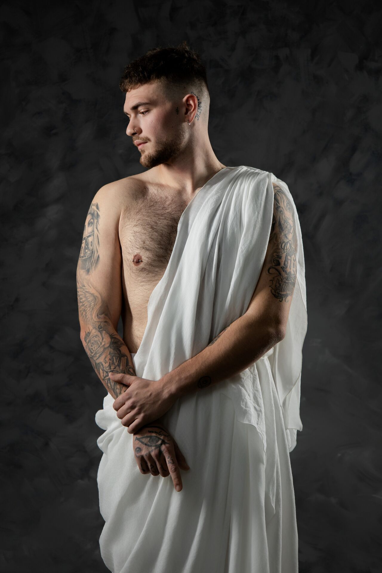 Artistic portrait series showing a shirtless figure draped in flowing white fabric against a dark dramatic background.