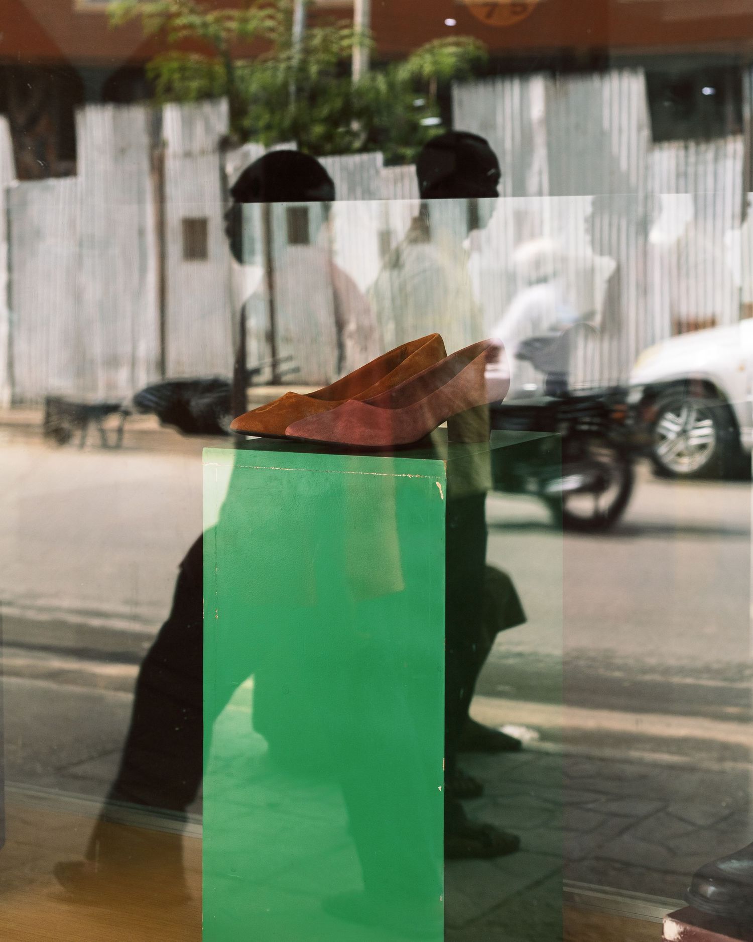 Abstract street photography reflection in a shop window, artistic visual storytelling in Tanzania by Naezi Eyes.