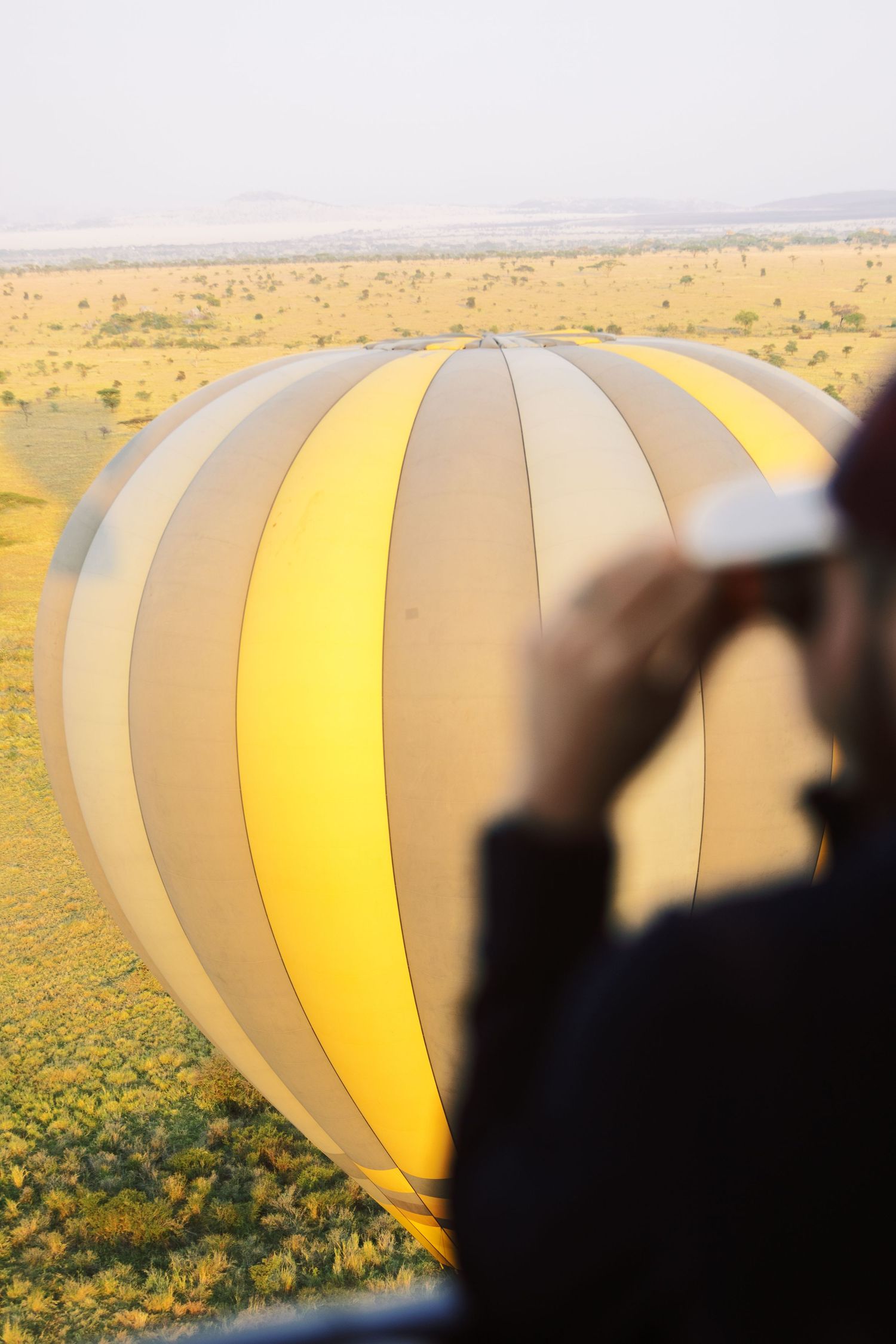Guest viewing the Serengeti plains from a hot air balloon, immersive POV adventure photography for tourism boards by Naezi Eyes
