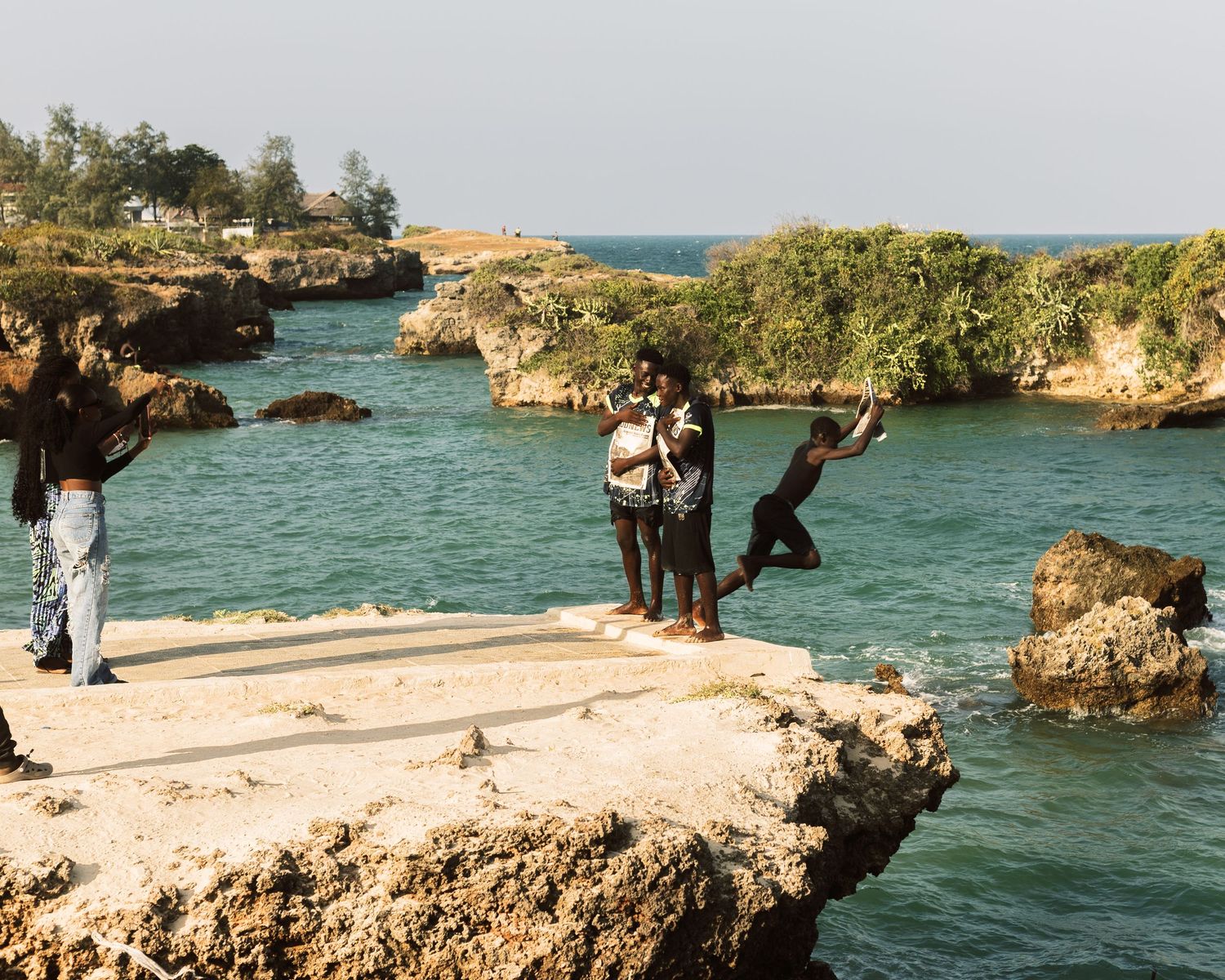 Youth standing on coral cliffs overlooking the Indian Ocean, unscripted lifestyle photography in Tanzania.