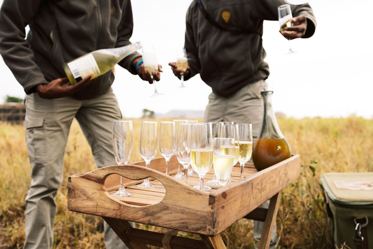 Candid photography of the Tour  pouring champagne, capturing the scale of Tanzanian national parks by Naezi Eyes.