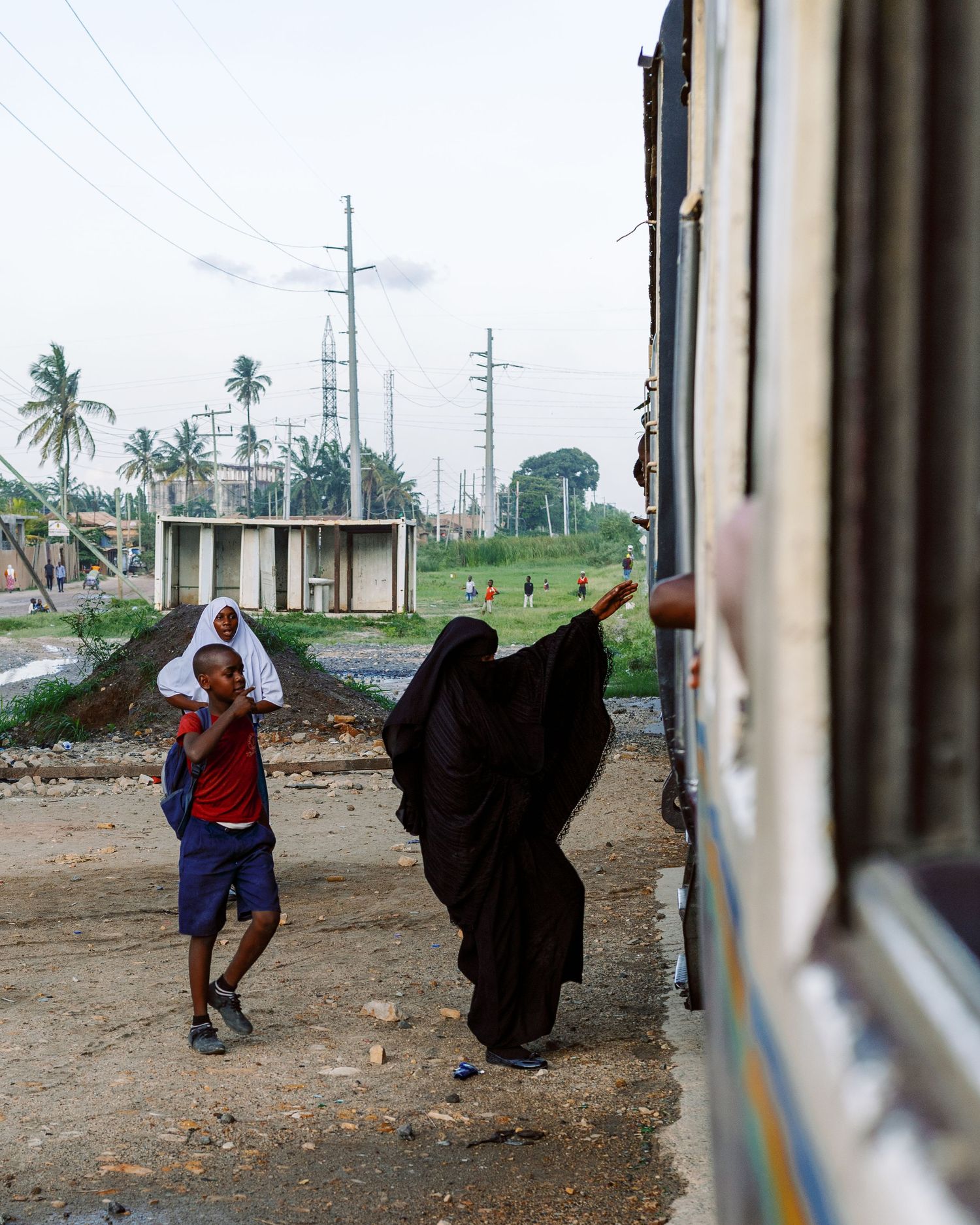 Woman in black abaya leaning out of a train window, capturing the emotion of travel and departure in Tanzania by Naezi Eyes.