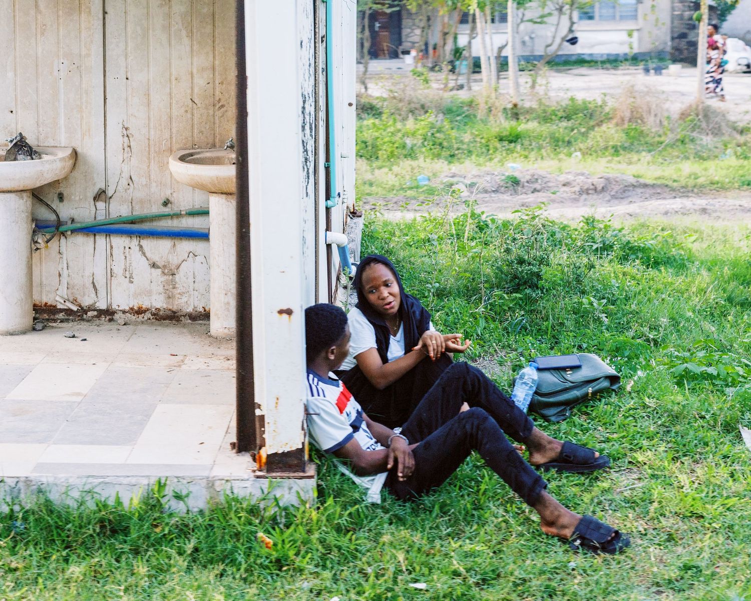 Couple sitting in an open train carriage doorway, cinematic railway travel photography across Tanzania by Naezi Eyes