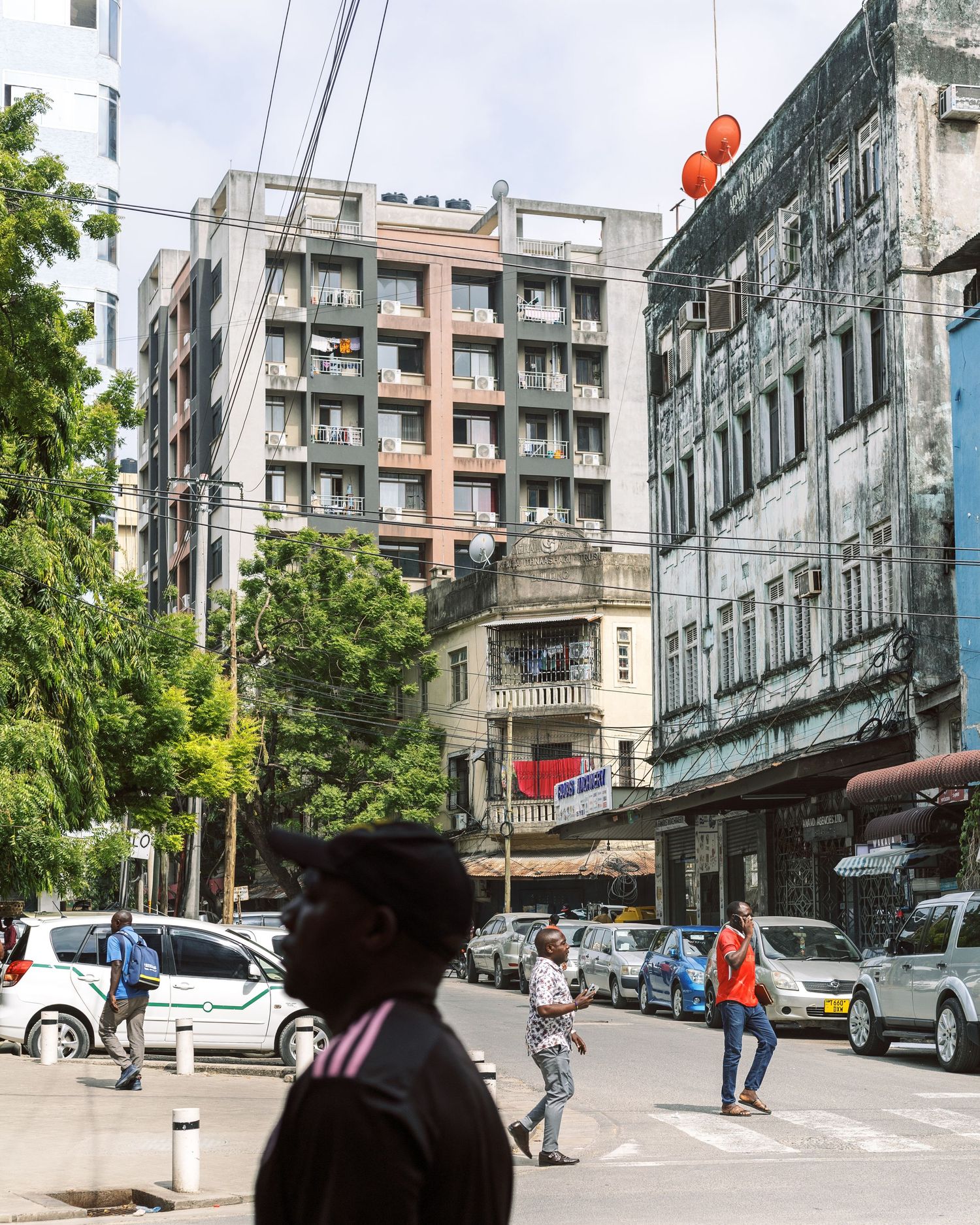 Busy street corner in Dar es Salaam with pedestrians and architecture, documenting the changing face of the African city by Naezi Eyes.