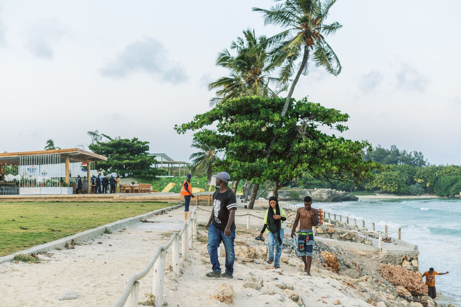 People walking along the white sandy coastline of Dar es Salaam, documenting the intersection of city and sea.