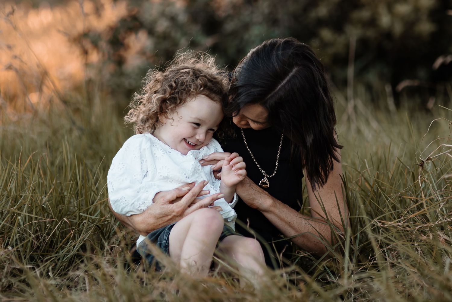 A heartwarming outdoor moment shared between parent and child sitting in tall grass.