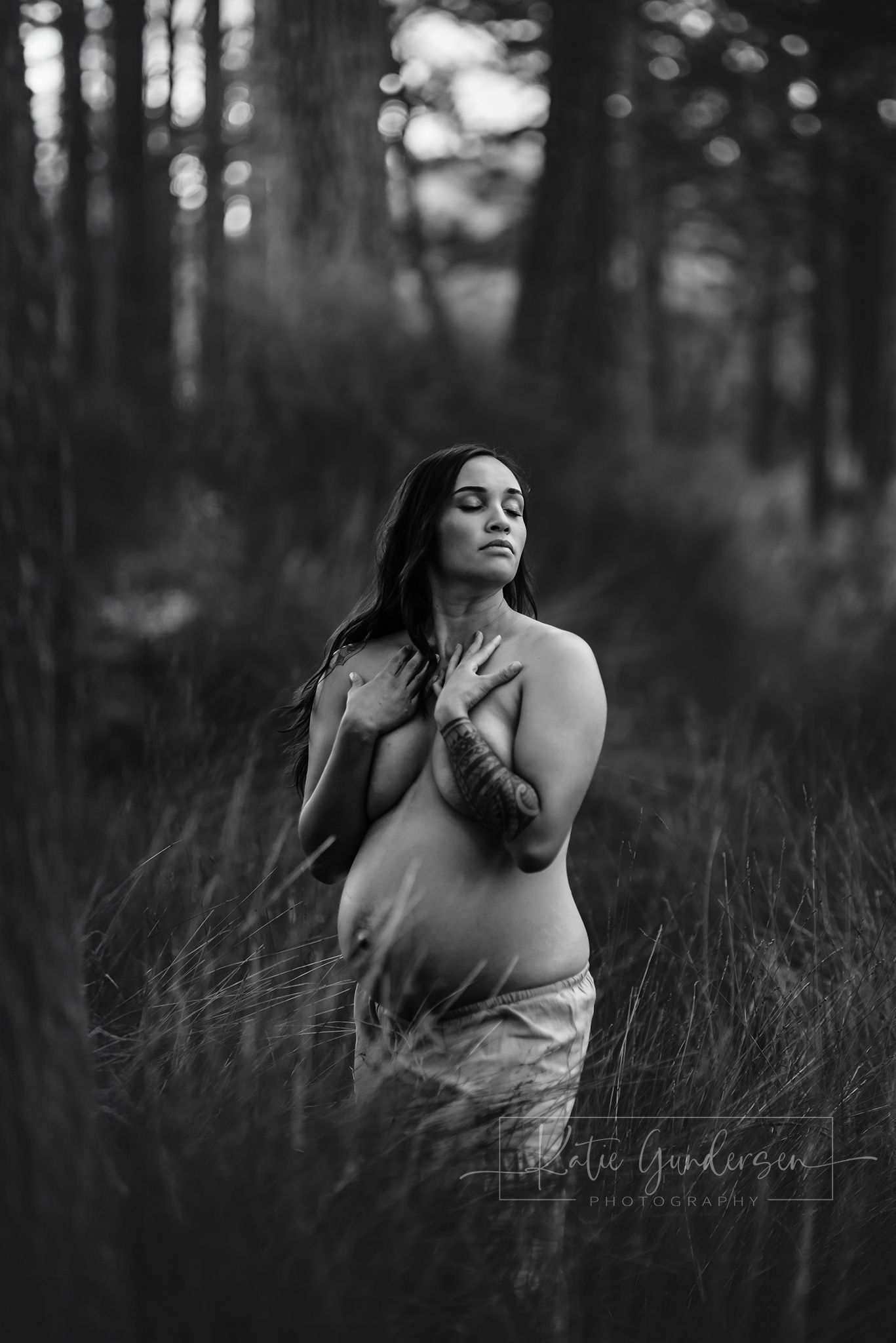 Artistic black and white maternity portrait in a misty forest setting.
