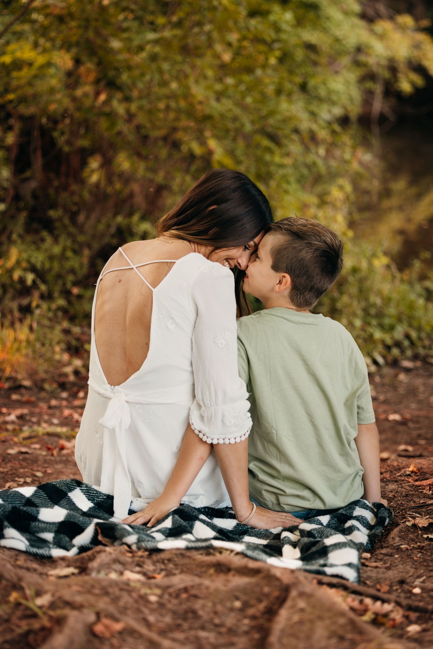 Couple sitting together on rocky ground surrounded by autumn foliage.