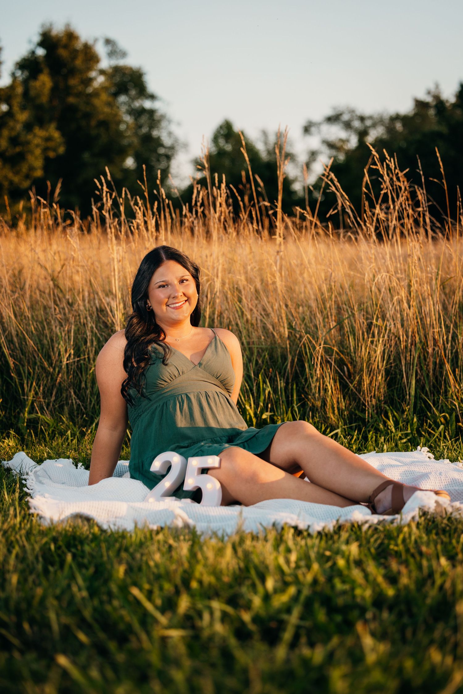 Outdoor portrait session in tall golden grass during sunset with white blanket.