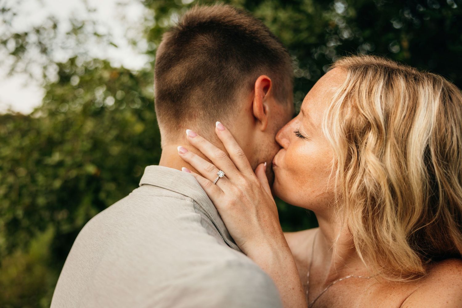 Romantic couple sharing tender moments in lush green outdoor setting.