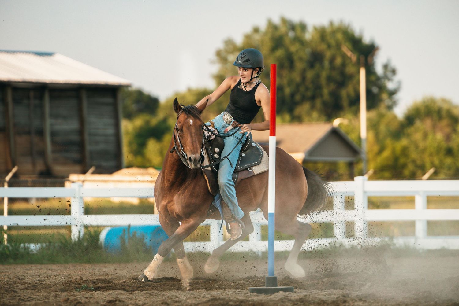 Horses kick up dust while racing through a barrel pattern in an arena.