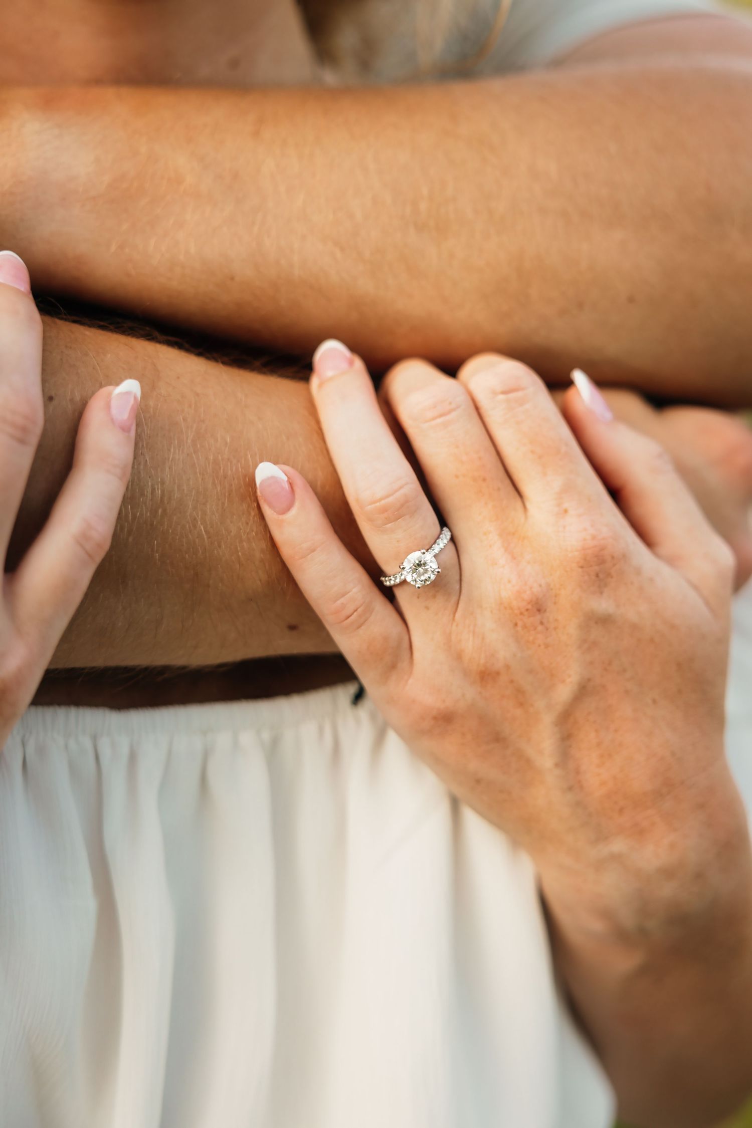 Close-up of hands with engagement ring showing tender embrace.