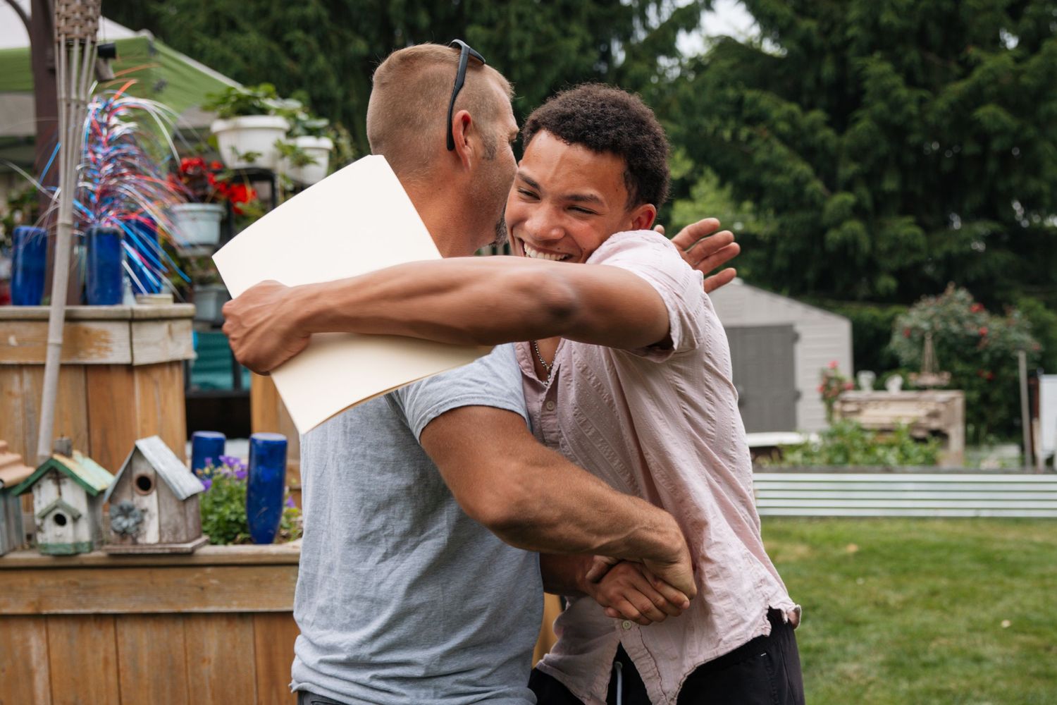 Friends embrace and celebrate at an outdoor gathering.