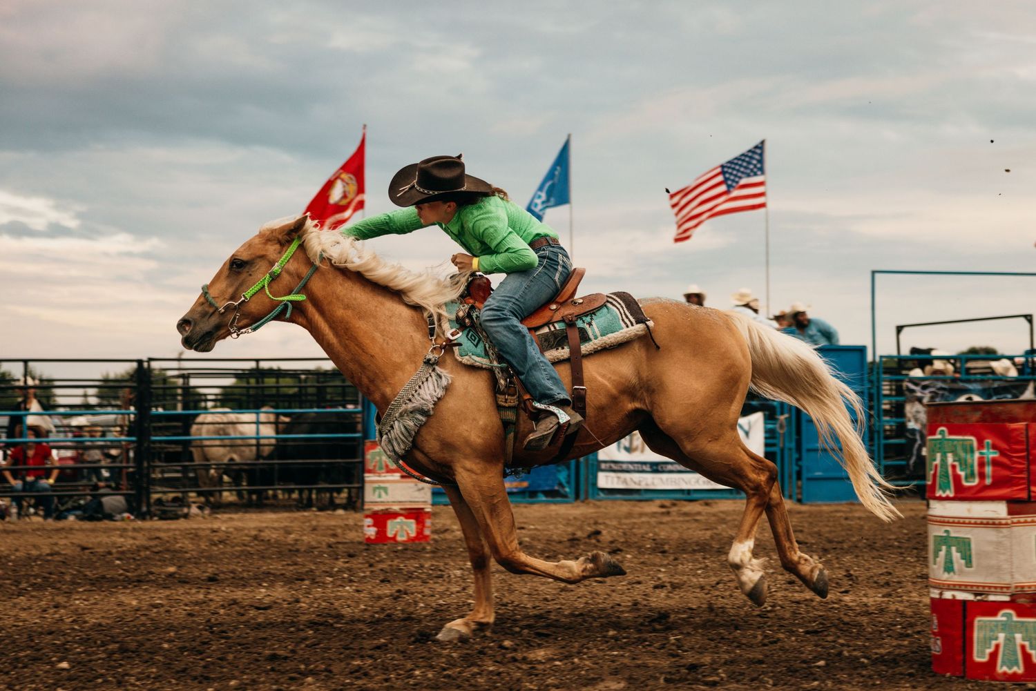 Rodeo competition sequence with riders racing horses under American and colorful flags.