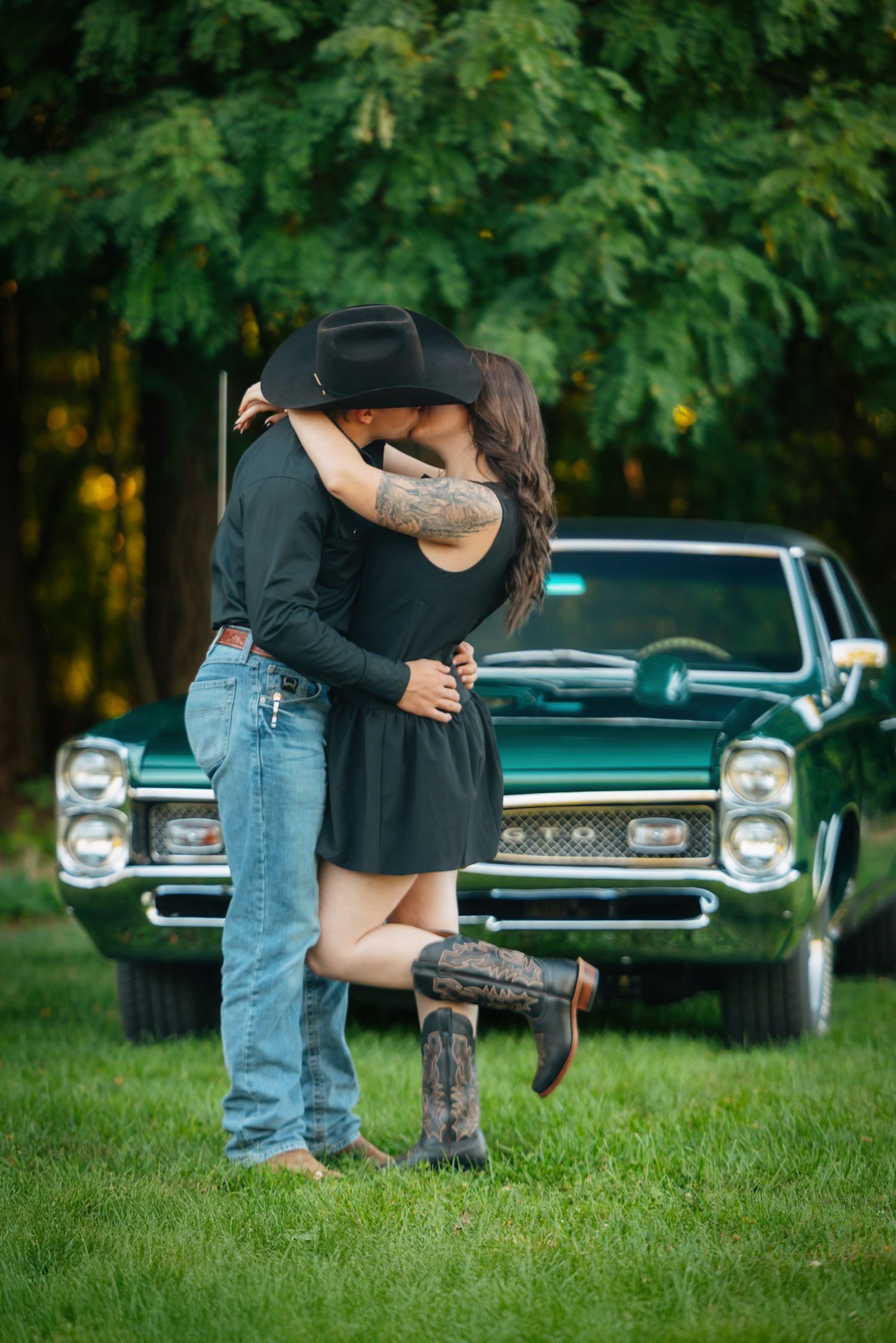 Romantic moments shared near classic cars with maple trees overhead.