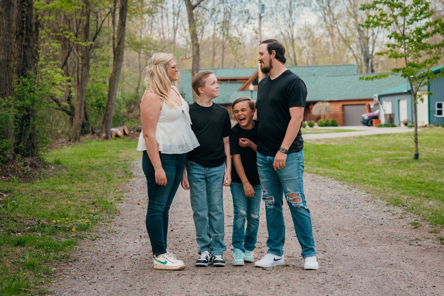 A family shares a candid moment together on a wooded path.